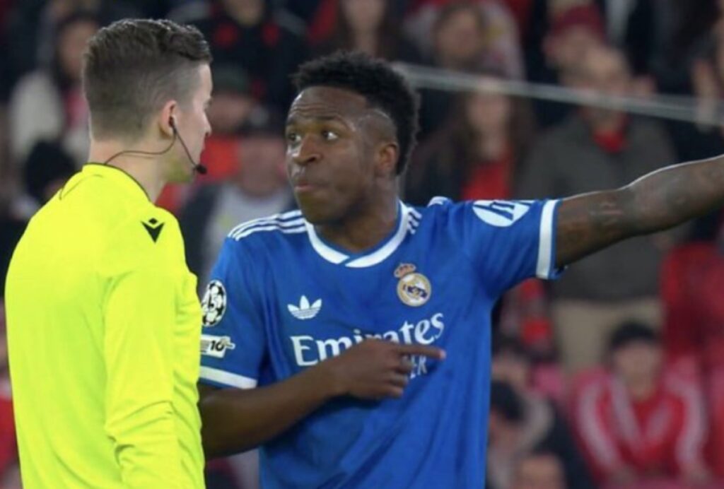 De acordo com o site Metrópoles, o jogador brasileiro Vinícius Júnior foi o responsável por abrir o placar para o Real Madrid em uma partida decisiva contra o Benfica, realizada nesta terça-feira, 17 de fevereiro, válida pelos playoffs da Champions League. O confronto entre as duas equipes ocorreu em um contexto de alta expectativa, dado o prestígio e a tradição de ambos os clubes no cenário europeu. O gol de Vinícius Júnior, segundo a publicação, foi um momento crucial no jogo, destacando a habilidade e o talento do atacante brasileiro em competições de alto nível. Ainda conforme informações do Metrópoles, o jogo ficou marcado por um incidente que levou o árbitro a acionar o protocolo antirracismo. Após o gol de Vinícius Júnior, houve manifestações na arquibancada que foram consideradas ofensivas e de teor racista, o que motivou a intervenção das autoridades responsáveis pela partida. O protocolo antirracismo, segundo a publicação, é uma medida adotada para combater e prevenir atos discriminatórios nos estádios, garantindo um ambiente mais seguro e respeitoso para todos os envolvidos. O site Metrópoles destaca que a ativação do protocolo antirracismo durante o jogo entre Real Madrid e Benfica reflete um esforço contínuo das entidades esportivas para lidar com questões de discriminação racial no futebol. A publicação enfatiza a importância de tais medidas para promover a inclusão e o respeito no esporte, além de proteger os atletas de comportamentos inaceitáveis. O episódio envolvendo Vinícius Júnior, segundo o site, reforça a necessidade de vigilância e ação imediata diante de qualquer sinal de racismo, assegurando que o futebol permaneça um espaço de diversidade e igualdade.