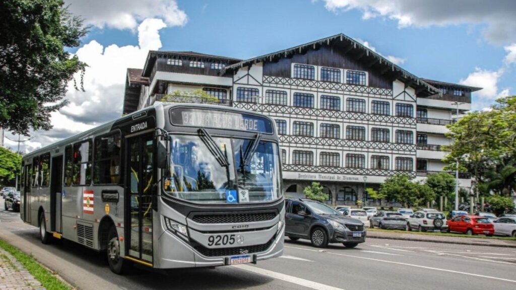 O **aumento na tarifa de ônibus em Blumenau** entrou em vigor nesta segunda-feira (23), impactando diretamente o custo do transporte coletivo para os usuários que optam pelo pagamento em dinheiro. Agora, a passagem custa **R$ 7**, conforme informações divulgadas pelo ND Mais. Este reajuste reflete a necessidade de adequação dos preços frente aos desafios econômicos enfrentados pelo setor de transportes, que incluem a inflação e o aumento dos custos operacionais. A decisão de alterar o valor da tarifa foi tomada após uma análise detalhada das condições financeiras do sistema de transporte público da cidade. Segundo a publicação, o novo valor da passagem em dinheiro visa garantir a sustentabilidade do serviço de transporte coletivo em Blumenau. O aumento é uma resposta às pressões econômicas que afetam o setor, como o aumento dos preços dos combustíveis e a necessidade de manutenção e renovação da frota de ônibus. Além disso, o reajuste busca assegurar a continuidade e a qualidade do serviço oferecido à população, evitando cortes de linhas ou redução na frequência dos ônibus. A medida, embora impopular, é vista como essencial para manter o equilíbrio financeiro do sistema de transporte público. O impacto do aumento da tarifa é significativo para os usuários que dependem do transporte coletivo em Blumenau. Para muitos, o reajuste representa um desafio adicional no orçamento mensal, especialmente para aqueles que utilizam o serviço diariamente. No entanto, segundo o site ND Mais, a administração municipal está ciente das dificuldades enfrentadas pelos cidadãos e busca alternativas para minimizar os efeitos do aumento, como a implementação de políticas de subsídio ou a promoção de programas de incentivo ao uso de cartões de transporte, que podem oferecer tarifas mais vantajosas em comparação ao pagamento em dinheiro.
