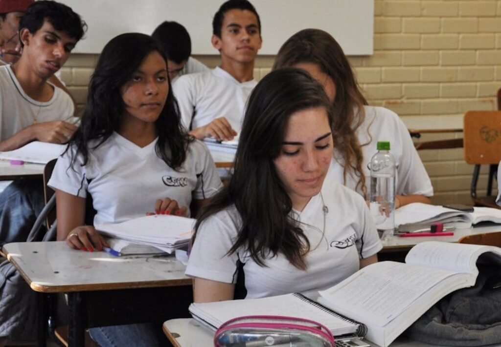 O que motivou a inclusão da Lei Maria da Penha nos currículos escolares? A medida visa educar crianças e jovens sobre a prevenção da violência contra mulheres, promovendo respeito e equidade desde cedo. Quais são os objetivos principais dessa regulamentação? Formar uma geração baseada no respeito e justiça, garantindo que meninas e mulheres possam viver sem medo. Como será implementado o ensino da Lei Maria da Penha nas escolas? O conteúdo será adaptado a cada nível de ensino, abordando direitos humanos e prevenção à violência. Qual é a importância de abordar esse tema na educação básica? Iniciar a discussão cedo ajuda a moldar atitudes e comportamentos futuros, prevenindo a violência de gênero. Como as universidades estão envolvidas nessa iniciativa? Foi assinado um protocolo para prevenir e enfrentar a violência de gênero em instituições de ensino superior. Quais são as expectativas para o futuro com essa medida? Profissionais formados com essa base atuarão em diversas áreas promovendo igualdade e enfrentando a violência. O que são as cuidotecas mencionadas pelo ministro Camilo Santana? São espaços nas universidades para cuidado de crianças, permitindo que mães estudem e trabalhem com dignidade. Como o Programa Mulheres Mil se relaciona com essa iniciativa? Ele visa aumentar a escolaridade e promover a inclusão socioprodutiva de mulheres em situação de vulnerabilidade. Qual é o impacto esperado dessas ações no combate ao feminicídio? Integram o Pacto Nacional Brasil Contra o Feminicídio, buscando reduzir a violência e promover a segurança feminina.