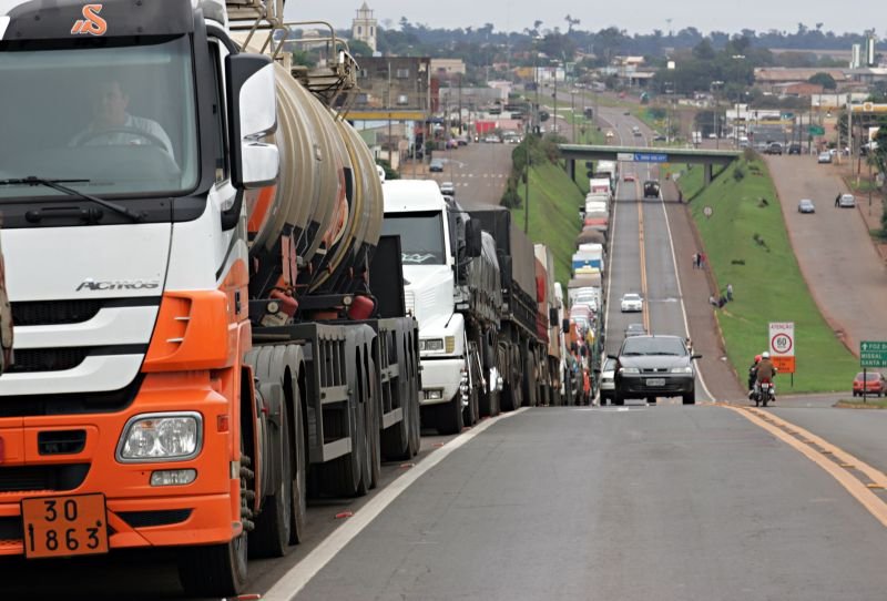 O que motivou o acordo entre governo e caminhoneiros? O acordo foi motivado pela necessidade de adiar uma possível greve nacional, focando no piso mínimo do frete e na manutenção da medida provisória do setor. Quais foram os principais pontos discutidos na reunião? A reunião abordou o piso mínimo do frete e a preservação do texto original da medida provisória no Congresso. O risco de greve está totalmente descartado? Não, o risco não está totalmente descartado. A mobilização continua com foco político na tramitação da medida provisória. Qual foi a posição do ministro Guilherme Boulos? Boulos destacou que a decisão de não fazer greve foi responsável, evitando politicagem e focando nos trabalhadores. Como os caminhoneiros veem o acordo? Os caminhoneiros veem o acordo como um ganho momentâneo, mas mantêm a pressão institucional no Congresso. Qual é a importância do diálogo para evitar greves? O diálogo é crucial, pois greves ocorrem quando há perdas. Com ganhos, a categoria tende a evitar paralisações. Quem participou da reunião? Participaram autoridades do governo e lideranças de entidades como CNTA, CNTTL e sindicatos regionais. Quais são as preocupações durante a tramitação legislativa? Há preocupação com possíveis alterações no texto da medida provisória durante sua tramitação no Congresso. O que o governo prometeu em relação à medida provisória? O governo prometeu defender o texto da MP no Congresso, evitando retrocessos nos pontos acordados. Quais medidas foram anunciadas para o mercado de combustíveis? Foi anunciado um reforço na fiscalização do mercado de combustíveis, com atuação de ANP, Polícia Federal, Senacon e Procons. Por que a fiscalização do mercado de combustíveis é importante? A fiscalização é importante para evitar práticas abusivas que impactam os custos dos caminhoneiros, especialmente no diesel. Quais são as novas medidas de controle da ANTT? A ANTT detalhou medidas como fiscalização eletrônica e cruzamento de dados para garantir o cumprimento do piso mínimo do frete. Quais são as possíveis sanções para empresas que descumprirem as regras? Empresas podem sofrer sanções como suspensão cautelar e até perda do registro em caso de reincidência. Como o acordo impacta a categoria dos caminhoneiros? O acordo traz um alívio temporário, mas a categoria continua mobilizada para garantir seus direitos no Congresso. Qual é o papel do WhatsApp na comunicação dos caminhoneiros? O WhatsApp é uma ferramenta de comunicação, mas as regras de privacidade dos grupos são definidas pela plataforma. Como o governo pretende garantir o cumprimento do acordo? O governo pretende garantir o cumprimento do acordo através de fiscalização e atuação política no Congresso.