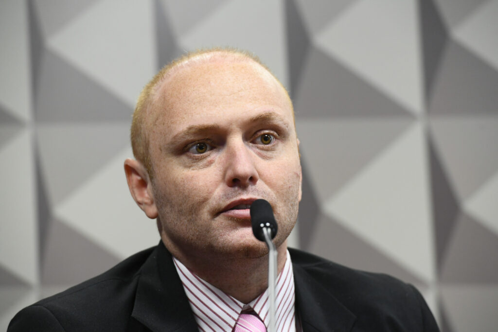 **Walter Delgatti Neto**, conhecido como o “**hacker de Araraquara**”, teve seu pedido de **saída temporária** negado pelo ministro Alexandre de Moraes. Delgatti está cumprindo uma pena de **oito anos de prisão** por invadir os sistemas do **Conselho Nacional de Justiça**. A decisão de Moraes reflete a gravidade das ações de Delgatti, que foram consideradas uma ameaça significativa à segurança e integridade dos sistemas judiciais do país, segundo a publicação da Gazeta do Povo. A defesa de Delgatti solicitou a reconsideração da decisão, argumentando que ele deveria ter direito a benefícios previstos na legislação penal, como a saída temporária. No entanto, segundo o site, o pedido foi negado com base na avaliação de que a concessão desse benefício poderia representar um risco à segurança pública, dado o histórico de Delgatti em relação a crimes cibernéticos. A decisão de manter Delgatti preso sem a possibilidade de saída temporária destaca a postura rigorosa das autoridades em casos que envolvem crimes cibernéticos de grande escala. O caso de Delgatti ganhou notoriedade devido à sua capacidade de acessar sistemas altamente protegidos e à repercussão de suas ações no cenário nacional. Segundo a publicação, a invasão aos sistemas do Conselho Nacional de Justiça não só expôs vulnerabilidades críticas, mas também levantou questões sobre a segurança digital das instituições públicas brasileiras. A decisão de Moraes, portanto, não apenas reafirma a seriedade com que o Judiciário trata crimes dessa natureza, mas também serve como um alerta para a necessidade de reforçar as medidas de segurança cibernética em órgãos governamentais.