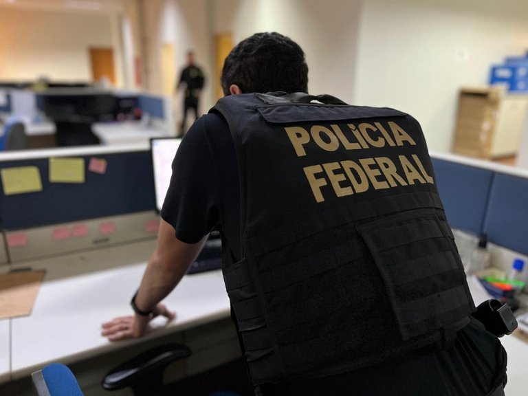 A **Polícia Federal (PF)** realizou uma operação significativa contra uma organização criminosa especializada em **lavagem de dinheiro** e **evasão de divisas**. Na quinta-feira, 26, a PF, sob a orientação da 5ª Vara Federal em Santos (SP), confiscou bens e valores que totalizam R$ 934 milhões. Esta ação faz parte da segunda fase da **Operação Narco Azimut**, que tem como objetivo interromper a movimentação de recursos provenientes do tráfico de drogas. Esses recursos eram movimentados através de uma complexa rede de empresas e terceiros, tanto no Brasil quanto no exterior. Como a operação foi conduzida? Cerca de 60 agentes federais foram mobilizados para cumprir 26 mandados, que incluíam ordens de prisão temporária e de busca e apreensão. A operação foi realizada simultaneamente em várias cidades, como São Paulo, Santos, Ilhabela, Taboão da Serra, e Balneário Camboriú, em Santa Catarina. Além disso, o Judiciário impôs restrições severas, proibindo qualquer movimentação empresarial ou transferência de patrimônio relacionado às atividades sob investigação. Qual é o histórico desta operação? Esta fase é um desdobramento direto de investigações anteriores, especificamente das operações **Narco Bet** e da primeira fase da **Narco Azimut**. As investigações revelaram que o grupo criminoso utilizava diversas modalidades financeiras para ocultar a origem do dinheiro. Os métodos incluíam o uso intensivo de papel-moeda, transferências bancárias de alto valor e, cada vez mais, a movimentação de **criptoativos**. Essas estratégias visavam dificultar o rastreamento pelas autoridades. Como os criminosos estruturavam suas operações? Os investigados utilizavam empresas de fachada para dar uma aparência de legalidade às transações ilícitas. Com o material apreendido, a PF busca aprofundar o entendimento sobre a extensão do esquema e identificar outros integrantes da organização criminosa. Quais são as consequências legais para os envolvidos? Os indivíduos envolvidos enfrentam acusações formais que podem resultar em condenações por **lavagem de capitais**, **evasão de divisas** e **formação de organização criminosa**. As penas para esses crimes são consideráveis, refletindo a gravidade das acusações. Por que essa operação é importante? Segundo a publicação, a ofensiva da PF representa um duro golpe financeiro contra o crime organizado, destacando a eficácia das autoridades em combater a lavagem de dinheiro e a evasão de divisas. A operação também ressalta a importância de ações coordenadas e bem planejadas para desmantelar redes criminosas complexas. Em resumo, a segunda fase da Operação Narco Azimut não apenas interrompeu a circulação de recursos ilícitos, mas também reforçou o compromisso das autoridades em combater o crime organizado de forma eficaz e abrangente. A apreensão de R$ 934 milhões é um marco significativo na luta contra o tráfico de drogas e suas ramificações financeiras.