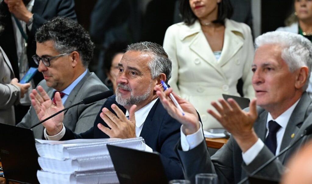 O que o relatório do PT sobre fraudes no INSS revela? O relatório do PT, apresentado por Paulo Pimenta, atribui ao governo Bolsonaro a responsabilidade por fraudes no INSS, destacando um ambiente político e normativo que facilitou essas irregularidades. Como Bolsonaro é relacionado às fraudes no INSS? Bolsonaro é apontado como peça-chave na criação de um "ecossistema" que permitiu fraudes, com apoio de auxiliares em cargos estratégicos e mudanças regulatórias que fragilizaram controles. Quais medidas do governo Bolsonaro facilitaram as fraudes? O relatório destaca a ampliação do prazo de revalidação de autorizações de desconto e o veto à proibição de transmissão de dados do INSS, enfraquecendo barreiras de proteção. Quem mais é responsabilizado no relatório? Além de Bolsonaro, o relatório propõe o indiciamento de Flávio Bolsonaro e José Carlos Oliveira, ex-presidente do INSS, por organização criminosa e facilitação do esquema. Qual foi o impacto financeiro das fraudes no INSS? As fraudes atingiram cerca de 5 milhões de aposentados e pensionistas, com um desvio total estimado em R$ 3,3 bilhões, segundo o relatório. Como o atual governo está lidando com as fraudes? O relatório destaca ações da CGU, Polícia Federal e AGU, como a Operação Sem Desconto, suspensão de descontos automáticos e ressarcimento às vítimas. Quantas pessoas foram indiciadas no relatório? O parecer propõe o indiciamento de 130 pessoas e o envio de outras 71 à Polícia Federal, totalizando 201 nomes entre pessoas físicas e jurídicas. Qual é a mensagem política principal do relatório? O documento sugere que a fraude no INSS prosperou devido às condições institucionais criadas pelo governo Bolsonaro, não sendo um evento isolado. Como a base governista reage ao relatório? A base governista argumenta que as fraudes não nasceram no atual governo, mas se expandiram entre 2019 e 2022, sob a administração de Bolsonaro. Quais entidades alertaram sobre as fraudes? O Ministério Público Federal, a Defensoria Pública da União e o Procon-SP alertaram sobre descontos indevidos e falhas de fiscalização, segundo o relatório. O que o relatório sugere sobre a estrutura normativa da Previdência? O documento afirma que a fraude capturou a estrutura normativa da Previdência, especialmente após o Decreto 10.537, de 2020, que ampliou descontos e fragilizou controles. Qual é a importância do Decreto 10.537, de 2020, no esquema? O decreto é visto como um ponto de inflexão na expansão das fraudes, permitindo mais descontos e alargando o tipo de entidade apta a operar com o INSS. Como o relatório caracteriza o papel de Bolsonaro no esquema? Bolsonaro é descrito como central na construção de um arcabouço institucional que favoreceu o esquema, por meio de auxiliares em cargos-chave. Quais são as consequências propostas pelo relatório? O relatório propõe indiciamentos por furto qualificado contra idoso, organização criminosa e improbidade administrativa, além de responsabilização política. Como o relatório busca diferenciar o atual governo do anterior? O documento tenta fixar a imagem do atual governo como responsável por desmontar o esquema, destacando ações corretivas e de ressarcimento às vítimas.