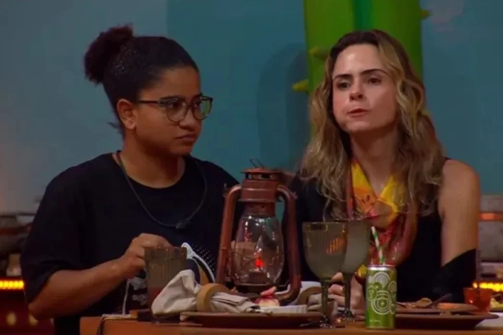 O que chamou a atenção na foto da família de Cowboy no BBB26? Durante a Festa do Líder, uma foto da família de Alberto Cowboy despertou curiosidade. Participantes notaram detalhes intrigantes, como roupas e posições, sugerindo possíveis mensagens ocultas. Por que Juliano Floss suspeitou de mensagens ocultas na imagem? Juliano foi o primeiro a levantar a hipótese ao observar como as pessoas estavam vestidas, sugerindo que poderia haver algo além de uma simples foto. Qual foi a observação de Ana Paula sobre a foto? Ana Paula notou que todas estavam de calça jeans, exceto uma pessoa de saia, destacando uma diferença visual que poderia indicar uma mensagem. Como Milena aprofundou a teoria sobre a foto? Milena observou que todos os homens usavam a mesma calça e bota, enquanto apenas uma das meninas estava diferente, sugerindo uma mensagem específica para Cowboy. Por que pequenos detalhes ganham importância no BBB26? Em momentos de confinamento e pressão, os participantes tendem a buscar significados ocultos em detalhes, influenciando suas percepções sobre o jogo. Qual é o contexto atual do BBB26? O BBB26 está na reta final, com mais duas eliminações previstas nos paredões de domingo e terça-feira, deixando nove confinados na disputa pelo prêmio. 🏆