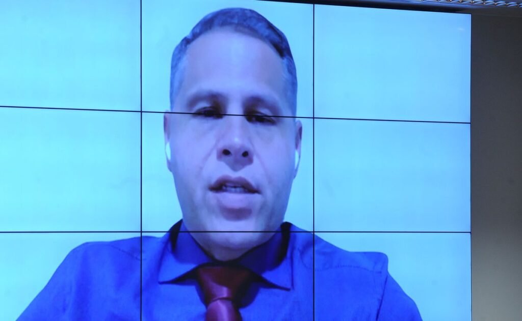 Uma decisão mudou o rumo da defesa de Eduardo Tagliaferro de forma tão brusca que a pergunta não é apenas o que aconteceu, mas por que isso aconteceu agora. O que levou a essa virada? A resposta começa em um gesto de confronto. A defesa que atuava no caso se recusou a participar de uma audiência de instrução. Foi um protesto direto contra a forma escolhida para intimar um perito que está na Itália. Em vez de carta rogatória ao governo italiano, houve citação, e isso abriu uma disputa processual que rapidamente saiu do campo técnico e ganhou peso político e jurídico. Mas por que a recusa da defesa teve um efeito tão forte? Porque, diante dessa negativa, Alexandre de Moraes decidiu destituir os advogados e nomear a Defensoria Pública da União para assumir a defesa. E é justamente aqui que muita gente trava a leitura e tenta entender: isso foi apenas uma resposta à ausência na audiência ou havia algo maior se formando nos bastidores do processo? A dúvida cresce porque o caso já vinha acumulando tensão. Antes dessa nova decisão, a audiência de instrução já havia sido anulada. O motivo? O defensor público Claudionor Barros Leitão se recusou a fazer perguntas, alegando que foi chamado em cima da hora para o ato. Se a audiência caiu por esse motivo, por que o processo voltou a se mover com tanta rapidez logo depois? A resposta está em uma nova marcação. Moraes designou outra audiência, agora para o dia 28 de abril. E o que parece apenas um reagendamento carrega um detalhe que quase passa despercebido: a troca da defesa não aconteceu isoladamente, mas no meio de uma sequência de impasses que vêm embaralhando o andamento do caso. E quem aparece nessa nova etapa? A Procuradoria-Geral da República listou cinco testemunhas. São delegados, um escrivão e um agente policial que atuaram na prisão de Tagliaferro em Caieiras, em São Paulo. Mas por que esses nomes importam tanto? Porque os relatos deles ajudam a explicar como uma investigação que começou em um cenário específico acabou tomando outro rumo. Qual era esse cenário inicial? A apuração envolvia suspeita de ameaça contra a esposa, Carla Bottoni Tagliaferro, com arma de fogo. Só que o que acontece depois muda tudo. Durante a atuação policial, foi identificado um aparelho em posse de Tagliaferro que levantou suspeita de uso institucional. A partir daí, houve apreensão do equipamento, e a investigação deixou de girar apenas em torno de violência doméstica e disparo de arma para alcançar também a possível violação de sigilo funcional. Mas há um ponto que chama ainda mais atenção. Os depoentes relataram que foram surpreendidos pela presença massiva da imprensa na porta da delegacia antes mesmo da chegada do perito. Como a imprensa já estava lá? Um dos jornalistas teria dito que em breve chegaria um “peixe grande” ao local. E é aqui que a maioria se surpreende, porque essa informação não responde a pergunta principal — ela cria outra ainda mais incômoda: quem sabia antes, e como sabia? Se isso já parecia sensível, por que o nome de Tagliaferro ganhou tanta projeção? Porque ele ficou conhecido após divulgar mensagens de um grupo de servidores dos gabinetes de Moraes no TSE e no STF. Esse é o ponto que recoloca todo o caso sob uma luz muito mais intensa. Não se trata apenas de uma troca de advogados ou de uma audiência remarcada. Trata-se de um personagem que passou a ocupar espaço central em uma controvérsia muito maior. E qual é a posição de Moraes diante disso? O ministro nega irregularidades na investigação de cidadãos por suposta desinformação e afirma que todos os procedimentos foram registrados nos autos. Mas essa resposta encerra o debate? Não exatamente. Porque, ao mesmo tempo em que sustenta a regularidade dos atos, a decisão de retirar os advogados constituídos e colocar a DPU no caso amplia a sensação de que o processo entrou em uma fase ainda mais delicada. No fim, o ponto principal é este: Alexandre de Moraes destituiu os advogados de Eduardo Tagliaferro após a defesa se recusar a participar da audiência e nomeou a Defensoria Pública da União para assumir o caso, remarcando a instrução para 28 de abril. Só que essa decisão, por si só, não fecha a história. Ela abre uma nova etapa em um processo que mistura conflito processual, testemunhos sensíveis, vazamento de informação e um nome que continua cercado de perguntas.