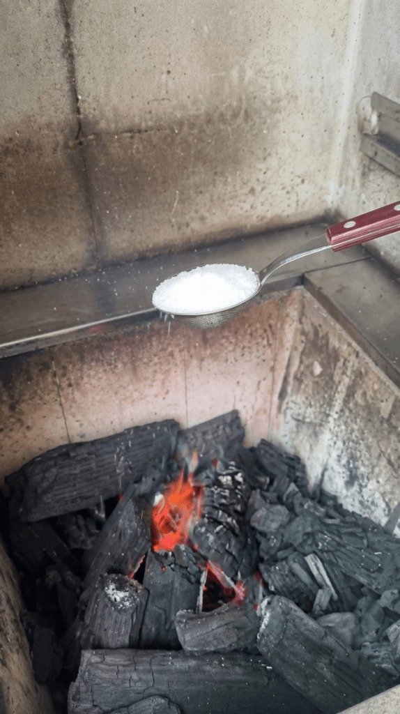 A parte mais irritante do churrasco talvez não seja esperar a carne ficar pronta, mas encarar aquela **nuvem de fumaça** que surge antes mesmo da primeira brasa aparecer. E se o problema não estivesse no carvão, mas na forma como ele é aceso? Por que tanta gente sofre sempre do mesmo jeito, com papel queimando rápido demais, fogo que apaga no começo e um cheiro forte que toma conta do ambiente? Porque, na maioria das vezes, o acendimento acontece de forma **irregular**, com combustão descontrolada e excesso de fumaça logo nos primeiros minutos. Só que existe uma maneira muito mais simples de mudar isso. Mas o que exatamente faz tanta diferença? Não é um equipamento caro, nem um truque complicado. O ponto está em usar um **ingrediente comum** junto com um elemento já conhecido no acendimento. E é justamente essa combinação que quase ninguém imagina que pode transformar completamente o início da churrasqueira. Qual é o efeito real dessa mistura? Em vez de uma chama instável, que sobe e morre sem força, ela favorece uma queima mais **uniforme**, mais limpa e muito mais previsível. Isso significa menos necessidade de soprar, menos esforço para manter o fogo vivo e, principalmente, muito menos fumaça grossa subindo no rosto de quem está tentando acender tudo. Mas por que isso funciona tão bem? Porque o maior vilão do acendimento não é apenas a falta de fogo, e sim a forma desordenada como ele se espalha. Quando a combustão acontece de maneira mais controlada, o carvão começa a reagir melhor, o calor se distribui com mais eficiência e as brasas se formam mais rápido. E é aqui que muita gente se surpreende: o segredo não está em colocar mais combustível, mas em fazer o fogo começar do jeito certo. Então qual é esse ingrediente? É o **açúcar**. Sim, algo simples, acessível e que, quando combinado com **álcool**, ajuda a criar uma queima mais estável. Mas há um detalhe que quase ninguém percebe: não basta jogar tudo de qualquer jeito sobre o carvão. A forma de montar faz parte do resultado. Como preparar? A orientação é cortar uma **lata ao meio** e usar uma das metades como recipiente. Dentro dela, coloque **álcool** e acrescente **uma colher de açúcar**, mexendo bem até misturar. Essa combinação deve ficar no centro do carvão, em um espaço aberto no meio da churrasqueira. Ao redor, o carvão é disposto como uma espécie de **cabana**, deixando uma pequena abertura para alcançar a chama. E depois, o que acontece? Borrifa-se um pouco de álcool sobre o carvão, acende-se um papel e aproxima-se com cuidado pela abertura. O fogo começa a se espalhar de forma rápida e uniforme, sem aquela cena clássica de ficar abanando, soprando ou tentando reacender várias vezes. O que vem em seguida muda tudo: em poucos minutos, o carvão vira **brasa pronta** para receber os alimentos. Mas isso realmente reduz a fumaça ou só acelera o processo? As duas coisas. Ao contrário de **óleos** ou outros combustíveis caseiros, a mistura de álcool com açúcar produz uma queima mais **limpa e estável**. É justamente essa estabilidade que evita a combustão irregular, responsável pela fumaça pesada e pelo cheiro forte que costuma incomodar tanto, especialmente em áreas menores. Então o maior benefício é só a praticidade? Não. Existe também uma mudança na experiência. Acender a churrasqueira deixa de ser a etapa mais chata e passa a ser algo muito mais confortável, rápido e eficiente. Menos fumaça, menos esforço e uma formação de brasas muito melhor desde o começo. E por que tanta gente ainda insiste nos métodos que dão errado? Talvez porque nunca tenha percebido que um ajuste tão simples pode alterar tudo. No fim, o ponto principal não é apenas adicionar **açúcar ao álcool**, mas entender que uma churrasqueira acende melhor quando o fogo nasce com controle. E quando isso acontece, o churrasco começa bem antes da carne tocar a grelha.