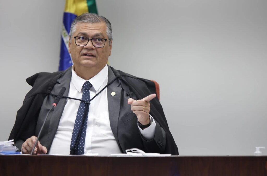 Quando uma CPI mira ministros do Supremo e até o procurador-geral da República, a pergunta não é só o que aconteceu, mas por que a reação veio tão rápido e tão dura. Quem reagiu? Antes de chegar ao nome, vale entender o tamanho do movimento. Um relatório apresentado na CPI do Crime Organizado pediu o indiciamento, por crimes de responsabilidade, de três ministros do STF e também do chefe da Procuradoria-Geral da República. Isso, por si só, já desloca o debate para um terreno explosivo. Mas o que torna esse episódio ainda mais sensível? O ponto central está no alvo escolhido. Não se trata de figuras periféricas da República, mas de integrantes do núcleo mais alto do sistema de Justiça. E é justamente aí que surge a dúvida seguinte: qual foi a justificativa para colocar esses nomes no centro do relatório? Segundo o documento, um dos ministros teria adotado conduta incompatível que comprometeria apurações da CPI. Outro é citado por atuar em processos nos quais, de acordo com o relatório, não deveria ter atuado, além de ter restringido o alcance das investigações. Um terceiro aparece por julgamentos em situação de suspeição e por vínculo com investigados pela Corte. Já o procurador-geral é acusado de omissão e falha no cumprimento de suas atribuições. Parece direto, mas há um detalhe que quase ninguém percebe: a resposta a esse relatório não ficou restrita ao campo técnico. Foi aí que surgiu uma manifestação pública que mudou o peso político do caso. Um ministro do Supremo classificou o pedido como “injustiça” e afirmou solidariedade aos colegas atingidos e também ao procurador-geral. Mas por que essa fala chama tanta atenção? Porque ela não se limitou a defender pessoas. Ela atacou o rumo da própria comissão. Na avaliação feita publicamente, a CPI desviou o foco dos trabalhos. E isso abre uma nova pergunta: desviou de quê, exatamente? A resposta veio em tom de crítica frontal. Para esse ministro, investigar crime organizado sem tratar de milicianos, traficantes de drogas, vendedores de armas ilegais, garimpos ilegais, facções que controlam territórios, matadores e pistoleiros seria uma irresponsabilidade. E é aqui que muita gente se surpreende: a discussão deixa de ser apenas sobre indiciamentos e passa a ser sobre o verdadeiro objeto da CPI. Se a comissão foi criada para enfrentar o crime organizado, por que o centro do relatório acabou recaindo sobre ministros do STF e o PGR? Essa é a pergunta que atravessa todo o episódio. E o que acontece depois muda o sentido da disputa: o debate passa a opor duas narrativas muito diferentes. De um lado, o relator da CPI, senador Alessandro Vieira, sustenta que “ninguém está acima da lei”. Ao apresentar o relatório, ele afirmou que a comissão enfrentou limitação de recursos e barreiras políticas e institucionais, especialmente quando fatos ligados a figuras imponentes da República começaram a ser investigados. Mas o que essa fala sugere? Sugere que, na visão do relator, houve obstáculos justamente quando a apuração se aproximou de nomes poderosos. Só que a reação do outro lado foi igualmente forte. O ministro que saiu em defesa dos colegas afirmou que existe, por parte de alguns, o equívoco de apontar o STF como o “maior problema nacional”. E foi além: chamou isso de “gigantesco erro histórico”. Por que usar uma expressão tão pesada? Porque, no fundo, a disputa não é apenas jurídica. Ela é institucional, política e simbólica. Ao defender o Supremo e a Procuradoria, ele argumentou que ambos têm um conjunto relevante de decisões contra o crime organizado no Brasil, dentro de suas competências constitucionais, alcançando quadrilhas armadas, crimes políticos e facções em geral. Mas há outra camada nessa história. Quando um ministro do STF sai publicamente em defesa de colegas após um pedido de indiciamento vindo de uma CPI, o gesto não serve apenas como solidariedade. Ele também funciona como recado. Recado de que, na visão dele, o foco foi trocado. Recado de que o alvo escolhido pela comissão revela mais do que uma simples investigação. E recado de que as consequências desse movimento podem ir além do relatório. No fim, o nome que fez essa defesa foi Flávio Dino. Ele chamou o pedido de indiciamento de “injustiça”, disse que a CPI desviou seu foco e manifestou apoio a Alexandre de Moraes, Dias Toffoli, Gilmar Mendes e a Paulo Gonet. Só que o ponto mais delicado talvez não seja esse. O mais delicado é o que fica no ar depois disso: quando uma comissão criada para investigar o crime organizado termina confrontando o topo do Judiciário e da Procuradoria, a crise deixa de ser sobre um relatório e passa a ser sobre quem está tentando definir o verdadeiro centro do poder.