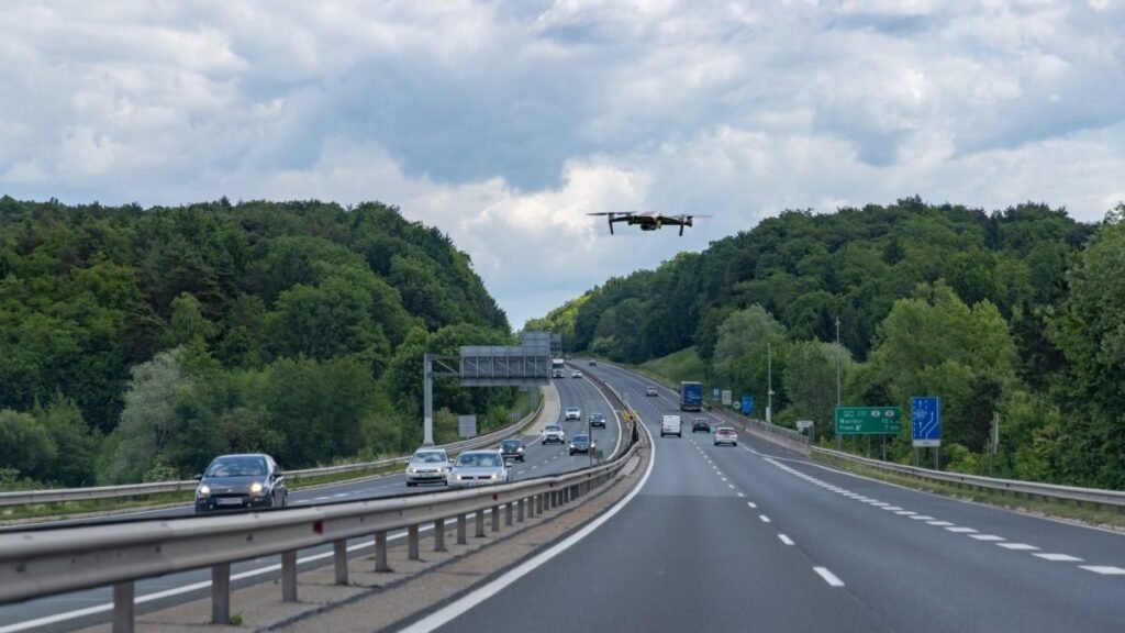 Você pode estar sendo filmado do alto sem perceber, e isso já está pesando no bolso de muita gente. Mas como alguém recebe multa sem nem ser parado na estrada? A resposta está em uma mudança silenciosa na fiscalização, que deixou de depender apenas da viatura no acostamento ou do agente visível à distância. Agora, parte desse olhar vem de cima, acompanhando o trânsito em tempo real e registrando o que antes passava despercebido em curvas, pontos cegos e trechos de grande movimento. E o que exatamente está sendo flagrado? Mais do que muita gente imagina. Entre as infrações que entram nesse monitoramento estão o uso do acostamento para circular ou ultrapassar, o manuseio do celular ao volante e a falta do cinto de segurança, tanto para motoristas quanto para passageiros. Também entram no foco veículos pesados em faixa proibida. Parece simples, mas há um detalhe que quase ninguém percebe: muitas dessas condutas acontecem justamente quando o motorista acredita que não há fiscalização por perto. Então quer dizer que não é mais preciso abordagem imediata? Em muitos casos, não. As imagens captadas podem servir para o registro da infração sem que o veículo seja parado naquele momento. Isso amplia o alcance da fiscalização e muda a lógica de quem ainda dirige pensando apenas no radar fixo, na viatura estacionada ou no agente à margem da rodovia. O que acontece depois muda tudo: a infração pode ser identificada por videomonitoramento, registrada e transformada em autuação mesmo sem contato direto na hora. Mas isso vale para qualquer situação? Não exatamente. O uso dessa tecnologia está ligado ao monitoramento de rodovias federais, especialmente em trechos de grande fluxo e áreas urbanas mais complexas, onde o campo de visão tradicional é menor e a interferência no trânsito pode atrapalhar a ação dos agentes. E é aqui que muita gente se surpreende: o objetivo não é apenas punir mais, mas enxergar melhor onde a fiscalização terrestre teria menos eficiência. Quem está por trás disso? A Polícia Rodoviária Federal ampliou o uso de drones em rodovias federais de diversos estados. Minas Gerais e Santa Catarina aparecem entre os destaques dessa operação, segundo o próprio órgão. Esses equipamentos funcionam como olhos aéreos, enviando imagens aos agentes e permitindo acompanhar o comportamento dos veículos em tempo real. Em alguns casos, além da multa sem abordagem imediata, viaturas ainda podem ser acionadas mais adiante. Mas existe respaldo para esse tipo de fiscalização? Sim. A operação, de acordo com as informações divulgadas, é respaldada pela Resolução 909 do Contran. Isso significa que o uso do videomonitoramento não está sendo feito de forma improvisada, e sim dentro de uma base normativa já prevista. Só que existe outra questão que reacende a curiosidade: se os drones já conseguem registrar infrações sem parar o veículo, até onde essa tecnologia pode ir? A resposta começa a aparecer quando se observa que alguns desses equipamentos não servem apenas para multar. Alguns drones contam com sensores térmicos capazes de identificar, por exemplo, superaquecimento em freios de caminhões. E esse é o ponto que muda a leitura de tudo: além de ampliar a fiscalização, a tecnologia também pode ajudar a prevenir acidentes antes que eles aconteçam. Então o drone está ali só para punir? Não necessariamente. Ele também aumenta a segurança dos agentes, reduz a necessidade de interferência direta no fluxo e permite monitorar áreas onde uma viatura teria atuação mais limitada. Só que, para o motorista, o efeito mais imediato é outro: aquela sensação de “ninguém viu” ficou muito mais arriscada. E qual é a principal conclusão disso tudo? A fiscalização aérea já é realidade, já está sendo usada em rodovias federais e já flagra infrações que muitos condutores ainda cometem por hábito ou distração. Uso de acostamento, celular ao volante, falta de cinto e circulação irregular de veículos pesados entraram de vez nesse novo campo de visão. Mas talvez o mais importante seja perceber que essa mudança não termina aqui. Quando a estrada passa a ser observada de cima, o que parecia invisível deixa de ser. E isso pode ser só o começo.