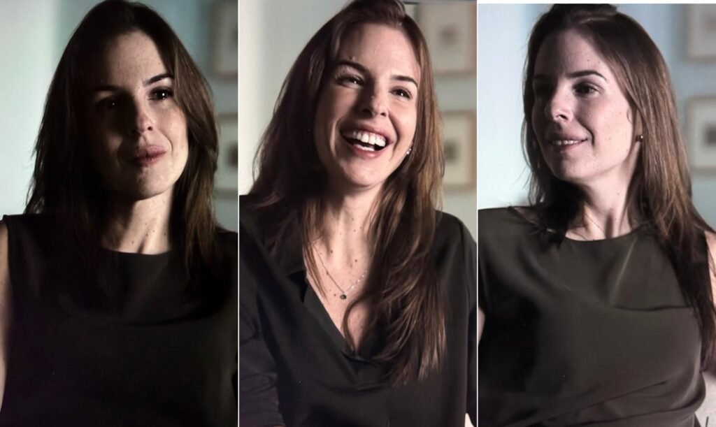 Ela volta a falar sobre um dos crimes mais chocantes do país, mas não começa pela noite do assassinato. Então por onde começa? Pela infância, pela casa onde viveu com os pais, Manfred e Marísia von Richthofen, e pelo ambiente que descreve como sem afeto. No documentário inédito, Suzane von Richthofen, hoje com 42 anos, revisita o caso pelo qual foi condenada a 39 anos de prisão, pena atualmente cumprida em regime aberto, e reconstrói a história sob a própria versão. O que ela diz sobre essa convivência familiar? Diz que cresceu em meio a cobrança, silêncio emocional e distância. Afirma que estudava o tempo todo, tirava notas altas e não havia demonstrações de amor entre pais e filhos. “Meu pai era **zero afeto**. Minha mãe ainda tinha um pouco”, relata. Em outro momento, resume a sensação de forma direta: os pais teriam construído um **abismo** dentro de casa. Esse distanciamento aparecia só na frieza cotidiana? Segundo Suzane, não. Ela afirma que o relacionamento dos pais era muito ruim e diz ter presenciado uma cena de violência quando era criança. Conta que viu o pai enforcando a mãe contra a parede durante uma discussão. Também relata ausência total de diálogo sobre temas íntimos e diz que, com o tempo, ela e o irmão, Andreas, foram ficando “invisíveis” dentro de casa. E o irmão, onde entra nessa história? Entra como refúgio. Suzane afirma que os dois criaram um mundo próprio dentro da casa, uma espécie de espaço separado dos pais. Essa ligação, segundo ela, funcionava como proteção em um ambiente que descreve como emocionalmente vazio. Quando essa dinâmica muda de forma decisiva? Quando Daniel Cravinhos passa a ocupar um lugar central em sua vida. Suzane sugere que o espaço deixado pela família foi preenchido por ele. O namoro avança, a resistência dos pais cresce e o conflito dentro de casa se intensifica. A mãe, segundo ela, dizia que Daniel a puxaria “para o fundo do poço”. Como esse relacionamento se desenvolveu? Em segredo e com mentiras cada vez mais frequentes. Suzane conta que saía de casa dizendo que ia para o karatê, mas seguia para a casa de Daniel. Diz também que, escondida dos pais, conheceu o litoral de São Paulo, alugava carro com ele e vivia experiências que associava ao mundo que queria viver. Quando as mentiras foram descobertas, afirma, a casa virou uma guerra. Esse conflito chegou a agressão? Segundo o relato dela, sim. Suzane afirma que levou um tapa do pai tão forte que seu rosto virou para o lado. A partir daí, a ruptura familiar teria se aprofundado ainda mais. Qual foi o ponto de virada? Ela aponta a viagem dos pais à Europa por 30 dias. Nesse período, Daniel teria ido morar com ela na casa da família. Suzane descreve esse mês como de “**liberdade total**” e diz que foi um sonho que não queria ver acabar. Também afirma que aquele período mudou tudo. Mas quando a ideia do crime aparece? De forma gradual, segundo a própria narrativa. Suzane diz que não falavam diretamente em matar os pais, mas repetiam que seria muito bom se eles não existissem. Aos poucos, essa ideia teria ganhado forma até se tornar concreta. Ela tenta se afastar da execução? Sim, mas sem negar a responsabilidade. Suzane afirma que não construiu a arma do crime e sustenta que não participou diretamente da execução. Diz que, na noite do assassinato, ficou no andar de baixo, no sofá, com as mãos nos ouvidos para não escutar o que acontecia no pavimento superior. Ainda assim, admite: **sabia**. E reconhece que poderia ter impedido. “A culpa é minha. Claro que é minha”, afirma. O que aconteceu naquela noite? Manfred e Marísia von Richthofen foram assassinados a pauladas em **31 de outubro de 2002**. O homicídio foi planejado por Suzane e executado pelos irmãos **Daniel e Cristian Cravinhos**. O documentário fica só no passado? Não. Ele também mostra a vida atual de Suzane. Sem data oficial de lançamento e com título provisório de **“Suzane vai falar”**, o filme de quase duas horas teve pré-estreia restrita na Netflix. Nele, ela aparece ao lado do marido, o médico **Felipe Zecchini Muniz**, que relata ter entrado em contato com ela pelo Instagram para encomendar sandálias customizadas para as três filhas. As meninas aparecem em cenas domésticas, assim como o filho pequeno de Suzane. E como ela encerra esse retorno ao passado? Tentando marcar uma separação entre quem foi e quem diz ser hoje. Afirma que a mulher que participou do assassinato dos pais ficou no passado. Diz que essa Suzane “morreu junto” com Manfred e Marísia, fala em fé, em redenção e declara que, ao olhar para o filho, sente a certeza de que Deus a perdoou. Ainda assim, admite que não escapa da própria história: continua sendo reconhecida, observada e fotografada em situações comuns do dia a dia.