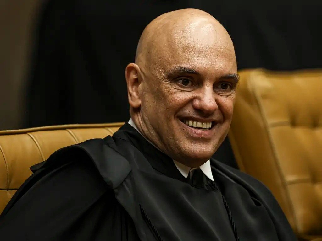 A prisão aconteceu de manhã, mas o que realmente chama atenção é outra coisa: **militares foram detidos pelo Exército por determinação direta de Alexandre de Moraes**. Como isso ocorreu tão rapidamente? A resposta começa no momento em que o **Supremo Tribunal Federal** rejeitou os primeiros recursos apresentados contra condenações ligadas à suposta tentativa de golpe de Estado. Mas por que a ordem foi executada agora, e não depois? Porque, segundo a decisão, já havia base para o **início da execução das penas**. Isso significa que a rejeição desses recursos foi suficiente para acionar os mandados de prisão definitiva. Só que essa resposta abre outra pergunta: quem exatamente foi alcançado por essa medida? Os nomes começaram a surgir ao longo da manhã. O **major da reserva Ângelo Denicoli** foi preso no **Espírito Santo**. Já o **tenente-coronel Guilherme Marques de Almeida** e o **subtenente Giancarlo Gomes Rodrigues** foram levados para o **Batalhão de Polícia do Exército, em Brasília**. E é aqui que muita gente para para pensar: se três foram presos, a operação terminou aí? Não. **Dois alvos seguem foragidos**: o **coronel da reserva Reginaldo Vieira de Abreu** e o **engenheiro Carlos Cesar Rocha**. E esse detalhe muda o peso da operação, porque mostra que a ação não se limitou a uma medida simbólica. Havia uma lista definida de condenados, e parte dela ainda não foi totalmente cumprida. Mas afinal, o que levou essas pessoas a esse ponto? Os mandados miram o grupo acusado de **espalhar informações falsas sobre as urnas eletrônicas**. Além disso, a **Procuradoria-Geral da República** sustenta que os militares teriam usado a estrutura da **Abin** para monitorar adversários políticos. Mas há um ponto que quase passa despercebido: essas condenações não são recentes. Elas ocorreram em **outubro do ano passado**. Então por que o caso volta a explodir agora? Porque o que acontece depois da condenação costuma ser menos visível, mas pode ser decisivo: a fase dos **recursos**. E foi justamente a rejeição dos primeiros recursos que abriu caminho para a execução imediata das penas. Só que isso não encerrou a controvérsia. Pelo contrário. A defesa de Denicoli reagiu e classificou a prisão como **“açodada”**, argumentando que ela ocorreu antes do esgotamento total dos recursos previstos na Constituição. E é nesse ponto que a discussão deixa de ser apenas penal e passa a ser também política e institucional. Mas qual é o tamanho dessas penas? A resposta ajuda a entender por que o caso ganhou tanta repercussão. **Denicoli recebeu 17 anos de prisão**, a punição mais alta entre os citados. **Abreu** foi condenado a **15 anos e meio**. **Rodrigues** recebeu **14 anos**. **Almeida**, **13 anos e seis meses**. As sentenças são em **regime fechado**, o que amplia ainda mais o impacto da decisão. Só que não para por aí. O STF também determinou o pagamento de **R$ 30 milhões por danos morais coletivos** e impôs a **inelegibilidade** de todos os envolvidos. E há mais uma consequência que pode ser ainda mais sensível para os militares: o tribunal enviou comunicação ao **Superior Tribunal Militar** para que seja analisada a **indignidade para o oficialato**, o que pode resultar em **perda de patentes e postos**. O que parecia ser apenas uma prisão, então, revela algo maior: uma cadeia de efeitos que atinge liberdade, carreira, imagem pública e futuro político. E por que o título fala no “**dono do Brasil**” Alexandre de Moraes? Porque essa expressão aparece como marca de crítica política ao alcance de suas decisões, especialmente quando uma ordem do ministro produz efeito direto até dentro da estrutura do **Exército**. O ponto central, no fim, é esse: **o Exército prendeu militares por ordem de Moraes após o STF rejeitar os primeiros recursos contra condenações já impostas**. Só que o caso ainda não se fecha por completo, porque há foragidos, há contestação da defesa e há consequências institucionais que ainda podem avançar.