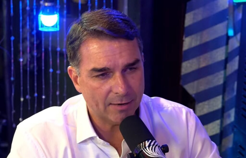 Ele votou a favor, foi criticado por aliados e depois disse que o projeto **não protege as mulheres** como promete. Como Flávio Bolsonaro explica essa contradição? Segundo o senador, a decisão ocorreu em meio a um momento em que sua atenção estava voltada para outro assunto: a autorização de **prisão domiciliar** para seu pai. Enquanto dava entrevistas sobre isso, a votação acontecia no Senado, e, de acordo com seu relato, ele não acompanhava integralmente a pauta naquele instante. Mas por que, mesmo assim, o voto foi favorável? Flávio afirmou, em entrevista ao podcast **Inteligência LTDA**, que sua assessoria o avisou sobre a **votação nominal** e informou que a orientação do partido era votar **sim**. Ele disse ainda que imaginava que uma emenda do senador **Carlos Portinho** resolveria grande parte dos problemas que via no projeto. A expectativa, portanto, era de que o texto pudesse ser ajustado antes de seguir adiante. E essa emenda foi votada? Não. Flávio declarou que não houve espaço para alterações naquele momento. Segundo ele, o projeto seria aprovado de qualquer forma e a esquerda estaria pronta para explorar politicamente um eventual voto contrário, apresentando-o como se fosse um posicionamento **contra as mulheres**. Nesse cenário, ele sustentou que a votação ocorreu de forma esmagadora e que houve uma manobra para votação nominal no texto principal, o que, segundo sua versão, impediu a análise da emenda. Então ele apoia ou rejeita a proposta? A resposta dele combina duas posições. De um lado, afirmou que votará a favor de qualquer projeto que entenda estar em **defesa das mulheres**. De outro, disse que, nesse caso, acredita que o texto **não cumpre esse papel**. Também declarou que não se pode ignorar a dor das mulheres, mas acrescentou que essa lei, da forma como está, **não será para protegê-las**. Por que as críticas cresceram tanto? Porque parte da base bolsonarista passou a atacá-lo após o voto favorável, inclusive com o uso do termo **“feministo”**. Como ele respondeu? Disse que tentaram atacá-lo dessa forma, mas reafirmou que continuará apoiando propostas que considere benéficas às mulheres. Ao mesmo tempo, reforçou que, no caso do chamado **PL da Misoginia**, concorda que o texto não entrega essa proteção. E qual foi o resultado da votação no Senado? A proposta foi aprovada por **unanimidade entre os senadores presentes**. Quem não participou? Estiveram ausentes **Angelo Coronel**, **Astronauta Marcos Pontes**, **Cid Gomes**, **Dr. Hiran**, **Eliziane Gama**, **Magno Malta**, **Mara Gabrilli**, **Otto Alencar**, **Professora Dorinha Seabra**, **Rogério Marinho** e **Sérgio Petecão**. Com a aprovação, o texto seguirá para a **Câmara dos Deputados**. Mas o que exatamente prevê o projeto? Ao **equiparar a misoginia ao racismo**, a proposta torna esse crime **imprescritível** e **inafiançável**, submetendo os infratores às mesmas punições aplicadas a casos de discriminação por **raça, cor, etnia, religião ou nacionalidade**. A pena prevista é de **um a três anos de reclusão**, além de multa, com cumprimento inicial em **regime fechado**. E se houver injúria motivada por misoginia? Nesse caso, a pena prevista passa para **dois a cinco anos de reclusão** e multa, podendo ser aumentada em **50%** se o crime for cometido por **duas ou mais pessoas**. Essa tipificação será incorporada à legislação que trata dos **crimes de racismo**. Há mais algum ponto relevante no texto? Sim. O projeto também estabelece que o juiz deverá considerar como **prática discriminatória** qualquer conduta que cause **constrangimento, humilhação, vergonha, medo ou exposição indevida**, em razão da **condição de mulher**. É esse o teor da proposta que Flávio Bolsonaro disse ter apoiado seguindo a orientação do partido, embora afirme acreditar que ela será **alterada na Câmara** ou até **radicalmente rejeitada**, se vier a ser pautada.