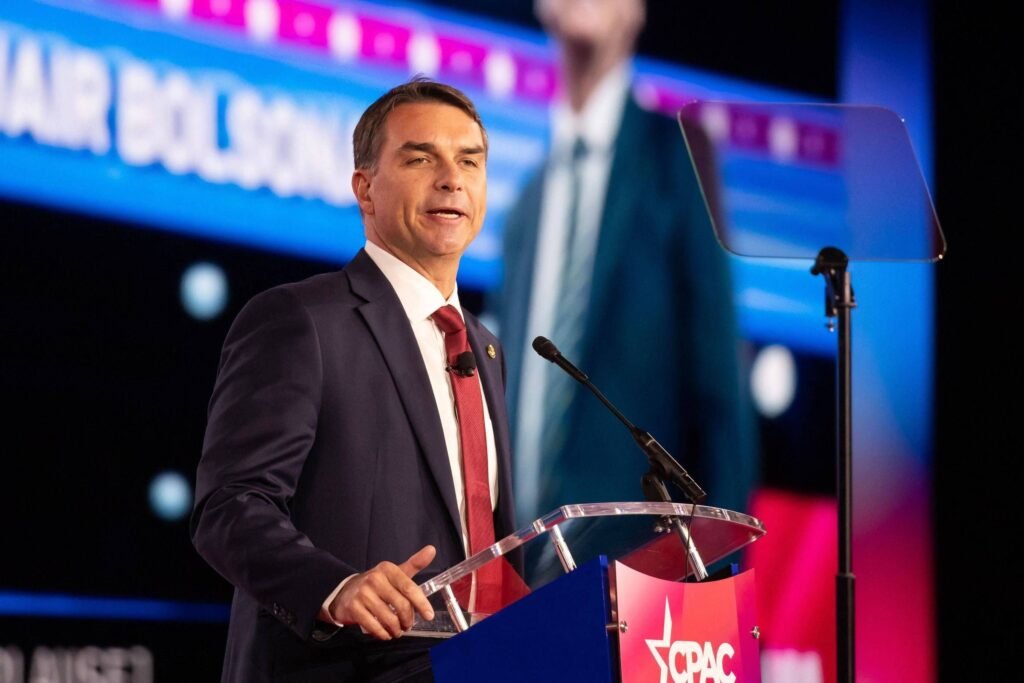 Por que Flávio Bolsonaro está seguindo os passos do pai em relação à desconfiança eleitoral? Flávio Bolsonaro, em discurso na Cpac, replicou a estratégia do pai, Jair Bolsonaro, ao questionar a integridade do processo eleitoral brasileiro, buscando apoio internacional para garantir "eleições livres e justas". Qual é o impacto do discurso de Flávio Bolsonaro na Cpac? O discurso reforça a imagem de populismo autoritário e antissistema, contrastando com a tentativa de moderação da sua pré-campanha, e busca atrair o eleitorado conservador e independente. Como Flávio Bolsonaro busca apoio internacional para as eleições brasileiras? Ele apelou por "pressão diplomática" do "mundo livre" para monitorar o processo eleitoral brasileiro, destacando a importância de eleições justas e liberdade de expressão. Quais são as semelhanças entre Flávio e Jair Bolsonaro em relação às eleições? Ambos utilizam retórica de desconfiança, alegando que fraudes podem comprometer a vontade popular, e buscam apoio internacional para validar suas preocupações. Por que Flávio Bolsonaro mencionou cartéis de droga em seu discurso? Ele usou a questão dos cartéis para justificar a necessidade de intervenção americana, ligando o narcotráfico à segurança dos EUA e buscando apoio para sua causa. Como Flávio Bolsonaro posiciona o Brasil no cenário internacional? Ele apresenta o Brasil como um potencial fornecedor de minerais críticos, essenciais para a segurança econômica dos EUA, e um campo de batalha decisivo para o futuro do hemisfério. Qual é a relação entre Flávio Bolsonaro e a direita radical global? Flávio se alinha com a direita radical ao adotar teorias conspiratórias, como a alegação infundada de que Joe Biden financiou a eleição de Lula, e ao criticar agendas progressistas. Como a teoria conspiratória sobre Joe Biden e Lula surgiu? A teoria foi propagada por Steve Bannon e Mike Benz, alegando que a Usaid financiou a eleição de Lula, e rapidamente ganhou força entre os apoiadores de Bolsonaro. Quais são as críticas de Flávio Bolsonaro às agendas progressistas? Ele critica a "agenda woke", a "agenda ambiental radical" e os "interesses da elite global", alinhando-se com narrativas da direita radical americana e europeia. O que Flávio Bolsonaro promete em relação a um possível segundo mandato de Trump? Ele sugere que um segundo mandato de Trump seria mais eficaz que o primeiro, e que um "Bolsonaro 2.0" também superaria o anterior, demonstrando apoio à concentração de poderes. Como o discurso de Flávio Bolsonaro pode afetar a democracia brasileira? Ao questionar a integridade eleitoral e buscar apoio externo, ele pode minar a confiança nas instituições democráticas e fomentar divisões políticas internas. Qual é a estratégia de Flávio Bolsonaro para atrair o eleitorado independente? Apesar do discurso radical, sua pré-campanha tenta projetar uma imagem de moderação para conquistar eleitores independentes, essenciais em uma disputa acirrada contra Lula. Como a retórica de Flávio Bolsonaro se compara à de outros líderes populistas? Assim como líderes populistas, ele utiliza teorias conspiratórias e retórica antissistema para mobilizar apoio, desafiando instituições democráticas e promovendo desconfiança. Quais são as possíveis consequências do discurso de Flávio Bolsonaro na Cpac? O discurso pode fortalecer laços com a direita radical global, mas também pode alienar eleitores moderados, complicando sua estratégia eleitoral no Brasil. Como Flávio Bolsonaro busca legitimar suas preocupações eleitorais? Ele apela para a comunidade internacional, destacando a importância de eleições justas e liberdade de expressão, tentando legitimar suas preocupações perante um público global.