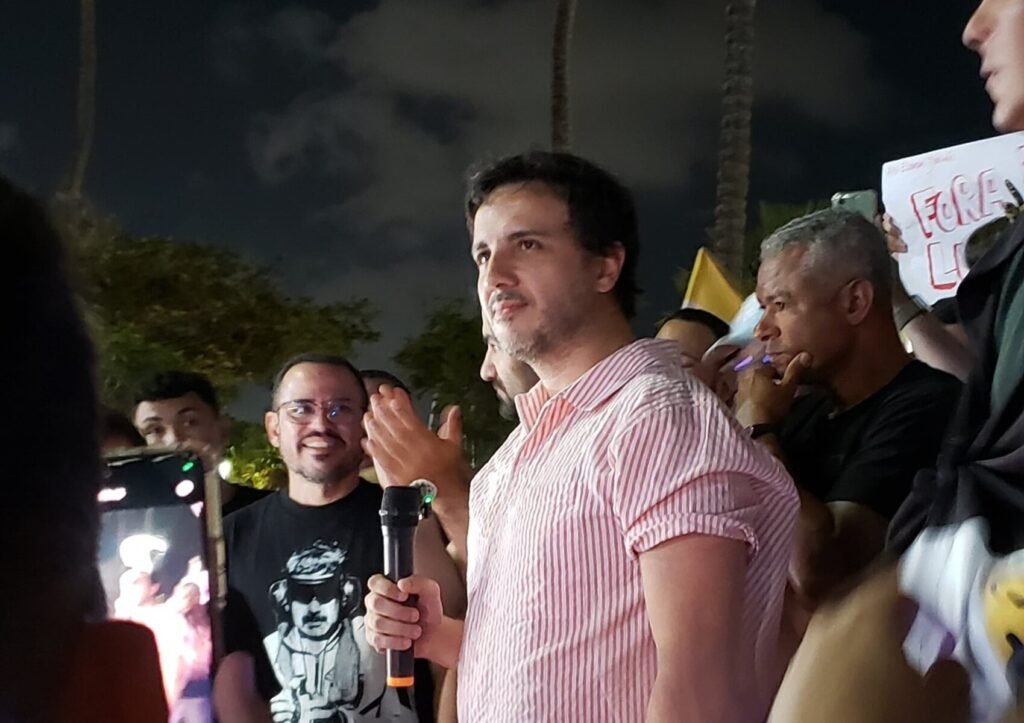 Bastou uma frase para acender mais um capítulo de um confronto que já vinha se arrastando e agora ganhou tom ainda mais duro. O que Flávio Bolsonaro disse sobre Renan Santos? Nesta segunda-feira, 6, o senador afirmou que o presidente do partido **Missão** “não tem condições psiquiátricas” de governar o país. A declaração foi dada ao podcast **Inteligência LTDA**, em meio à disputa entre dois nomes que se colocam como **pré-candidatos à Presidência da República**. Mas essa fala surgiu isoladamente ou fazia parte de uma escalada maior? Não foi um episódio solto. Os dois já vêm trocando ofensas desde o ano passado, em uma sequência de ataques públicos que elevou a tensão entre eles. Ao comentar Renan, Flávio adotou um tom de deboche e descreveu uma cena que, segundo ele, tornaria impossível levá-lo a sério. Foi nesse contexto que disse: “Esse cara não tem condições psiquiátricas de governar nada, de mandar em ninguém. Eu vi o cara fazendo um protesto outro dia em cima de um palco lá… ‘Flávio Bolsonaro impediu a revolução do nosso país’. O cara tá, irmão, com a espada na mão e um pirulito roxo na outra. O cara vai fazer revolução aonde? Não dá para levar a sério”. E a reação de Flávio ficou apenas no campo político? Não. O senador afirmou que pretende levar a disputa para o campo jurídico. O que ele disse exatamente? Segundo Flávio, Renan estaria ultrapassando o limite da crítica política e entrando no terreno da **calúnia**. Por isso, declarou: “Ele está cometendo diversas calúnias contra mim e vai ter que conversar com os advogados”. O que vinha sendo dito por Renan Santos para provocar essa resposta? Em 29 de dezembro, Renan acusou Flávio Bolsonaro e Jair Bolsonaro, ambos do **PL**, de “devolverem Lula ao poder”. A fala se somou a outras declarações agressivas feitas anteriormente. Renan também já havia chamado o senador de **“filho corrupto”** do ex-presidente e o desafiado diretamente para um debate. Como foi esse ataque? Em uma das falas reproduzidas, Renan afirmou: “Eu quero ver o filho corrupto deles no debate comigo. Flávio Bolsonaro, eu te aguardo. Eu quero acabar, eu quero acabar com sua raça, Flávio Bolsonaro. Você enterrou a nossa revolução, você enterrou nossa revolução. Mas nós não morremos, Flávio Bolsonaro.” E por que Renan associa essa crítica à volta de Lula ao poder? Porque ele relembrou a atuação do **MBL** nas ruas em defesa da **Operação Lava Jato** e afirmou ter experiência em derrotar o **PT**. Ao sustentar essa linha de ataque, declarou: “Você, Flávio Bolsonaro, você, Jair Bolsonaro, vocês devolveram Lula ao poder. O mesmo Lula que nós prendemos em 2018. Fomos nós na rua. Foi a Operação Lava Jato que nós apoiamos. Foi a nossa causa, foi a nossa coragem. Nós já vencemos eles antes, nós já os superamos antes. Nós temos PhD em como derrotar o PT.” Flávio reconhece Renan como adversário direto? A resposta dada por ele foi curta e direta: disse **“não conhecer” Renan**. Ainda assim, isso não impediu que respondesse publicamente às acusações e anunciasse a intenção de acionar advogados. Então, o que fica desse novo embate? De um lado, Flávio Bolsonaro afirma que Renan Santos “não tem condições psiquiátricas” de governar e diz que vai reagir judicialmente por **calúnia**. Do outro, Renan mantém os ataques, acusa Flávio e Jair Bolsonaro de terem “devolvido Lula ao poder”, chama o senador de **“filho corrupto”** e o desafia para debate. A frase de maior impacto dita por Flávio, que concentrou a nova rodada da disputa, foi esta: **“Esse cara não tem condições psiquiátricas de governar nada, de mandar em ninguém.”**