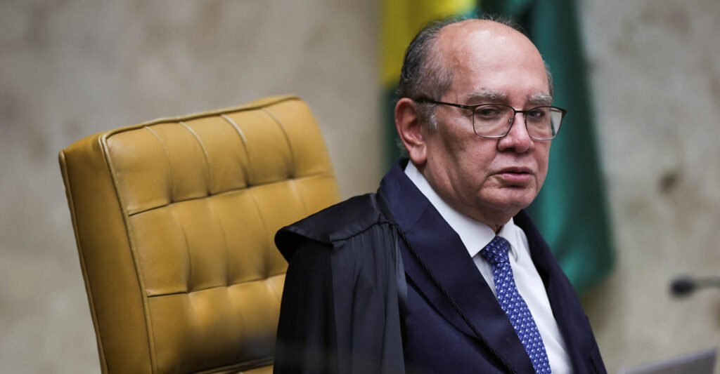 Uma frase dita no Supremo foi suficiente para lançar uma suspeita explosiva no ar, mas deixou para trás a pergunta que realmente importa: onde estão as provas? O que foi dito de tão grave assim? A declaração mencionou que dezenas de parlamentares estariam recebendo “mesada do jogo do bicho”. Não foi uma insinuação vaga, nem uma crítica genérica ao ambiente político. Foi uma fala direta, pesada, com potencial de abalar ainda mais um cenário já tensionado. Mas se a acusação é tão séria, por que ela chamou atenção não apenas pelo conteúdo, e sim pela ausência de sustentação pública? Porque o ponto central não foi só a denúncia verbal. O que provocou reação foi o fato de a afirmação ter sido feita sem apresentação de provas. E isso muda tudo. Quando uma fala dessa dimensão surge no meio de um julgamento sensível, a dúvida deixa de ser apenas sobre o que foi dito e passa a ser também sobre por que foi dito naquele momento. Mas em que contexto isso aconteceu? A declaração ocorreu durante uma sessão do Supremo Tribunal Federal. O tribunal discutia se a eleição para um mandato-tampão no Rio de Janeiro deveria ser direta ou indireta. Parece um debate técnico? Em parte, sim. Só que havia um pano de fundo político e institucional que tornava cada palavra mais carregada. E por que o Rio de Janeiro entrou no centro dessa discussão? Porque o caso envolve a sucessão no Estado em meio a uma crise institucional. Durante a sessão, foi lembrado que o presidente da Assembleia está preso. Foi nesse ambiente que a fala apareceu, associando o quadro político fluminense a uma contaminação mais profunda. Só que há um detalhe que quase ninguém percebe de imediato: o próprio ministro afirmou que o contexto não deveria orientar a decisão jurídica, embora devesse ser considerado diante da crise. Então a fala foi usada como argumento jurídico? Não exatamente. E é aqui que muita gente se surpreende. A declaração surgiu mais como retrato de um ambiente de deterioração do que como prova formal dentro do processo. Ainda assim, o impacto político foi imediato, porque a frase não ficou restrita a uma avaliação abstrata sobre o Estado. Ela citou um relato que, segundo o ministro, teria sido ouvido do diretor-geral da Polícia Federal, Andrei Rodrigues. E isso resolve a questão? Pelo contrário. Abre outra ainda maior. Se o relato foi mencionado em plenário, por que não vieram junto elementos concretos que o sustentassem? Essa é a lacuna que transforma uma fala forte em foco de controvérsia. O que acontece depois muda o peso de tudo: em vez de encerrar o debate, a declaração amplia a tensão sobre os limites entre percepção de crise, informação de bastidor e prova. Mas a sessão terminou com uma definição? Não. O julgamento foi suspenso após pedido de vista do ministro Flávio Dino. Ele defendeu que o STF aguardasse a conclusão do julgamento do ex-governador Cláudio Castro no Tribunal Superior Eleitoral. Segundo Dino, o acórdão ainda não publicado pode esclarecer pontos centrais do caso. Ou seja: no momento em que a frase mais explosiva surgiu, o processo em si nem sequer havia sido concluído. E os outros ministros, concordaram sobre o caminho a seguir? Também não. André Mendonça antecipou voto a favor de eleições indiretas, argumentando que seria preciso evitar indefinição política. Cristiano Zanin defendeu eleições diretas. Luiz Fux apoiou a escolha indireta. Já a presidente do TSE, Cármen Lúcia, afirmou que houve atuação indevida do STF ao analisar o caso antes da conclusão da corte eleitoral. Então qual é o ponto principal de tudo isso? É que, no meio de uma discussão sobre sucessão política no Rio, Gilmar Mendes afirmou ter ouvido que “32 ou 34 parlamentares” da Assembleia do Rio recebiam mesada do jogo do bicho, mas não apresentou provas da declaração. E é justamente essa combinação entre gravidade máxima e comprovação ausente que mantém o caso em aberto. A fala foi forte o bastante para dominar a atenção, mas insuficiente para encerrar a questão. E talvez seja exatamente por isso que ela continue ecoando: não pelo que comprovou, e sim pelo que deixou sem resposta.