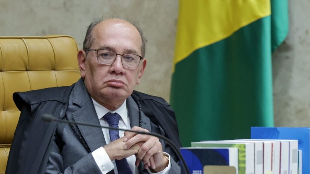 Uma **carona de volta a Brasília** acabou puxando um fio que agora alcança ministros do STF, um banqueiro preso, pagamentos milionários e um alerta vindo do próprio presidente da República. Mas o que, de fato, aconteceu com **Gilmar Mendes**? Segundo informação revelada pelo jornal **O Estado de S. Paulo**, o ministro usou, em **1º de janeiro de 2025**, um avião operado por empresa ligada ao empresário **Daniel Vorcaro**, dono do **Banco Master**. O voo saiu de **Diamantino, no Mato Grosso**, e seguiu para **Brasília** às **16h38**, de acordo com registros do Aeroporto de Brasília. Por que ele estava em Diamantino? Porque havia ido à posse do irmão, **Chico Mendes**, eleito prefeito da cidade com **56% dos votos em 2024**. Até aí, nada fora do comum. A dúvida começa depois: como esse retorno passou a chamar tanta atenção? A resposta está na aeronave. O avião era um **Phenom 300 da Embraer**, operado pela empresa **Prime You**, da qual **Vorcaro foi sócio**. E é justamente esse vínculo que transformou um deslocamento aparentemente simples em um caso de repercussão nacional. Gilmar sabia dessa ligação? Segundo o próprio ministro, **não**. Ele afirmou que aceitou uma carona oferecida por **Marcos Molina**, presidente do conselho da companhia formada pela fusão entre **BRF e Marfrig**, sem saber da relação do avião com o empresário do Banco Master. A empresa confirmou a viagem e informou que Molina possui **cota da aeronave**, mas negou qualquer relação pessoal ou comercial entre ele e Vorcaro. Então por que o episódio não parou aí? Porque esse voo não apareceu isolado. E é aqui que muita gente começa a se surpreender. De acordo com o **Estadão**, pelo menos **quatro ministros do STF** utilizaram aeronaves ligadas a Vorcaro. Além de Gilmar, os registros citam **Alexandre de Moraes**, **Dias Toffoli** e **Kassio Nunes Marques**. Quantos voos foram identificados? Os dados apontam ao menos **11 viagens** feitas por ministros e familiares em aviões ligados ao empresário. O nome que mais aparece é o de **Alexandre de Moraes**, com **oito deslocamentos registrados**, principalmente para **São Paulo**. Em um dos episódios, ele teria se reunido com Vorcaro no dia seguinte a um voo. E os outros ministros? **Dias Toffoli** teria usado aeronaves em viagens para um resort no interior. Já **Kassio Nunes Marques** confirmou deslocamento para **Maceió** em voo pago por uma advogada ligada ao **Banco Master**. Nenhum deles admite vínculo com o empresário. Mas há um detalhe que quase passa despercebido: a história dos voos ganhou outra dimensão quando surgiram informações sobre relações financeiras envolvendo o banco. Documentos da **Receita Federal** enviados à **CPI do Crime Organizado** indicam que o Banco Master pagou mais de **R$ 40 milhões**, em **2024**, ao escritório da advogada **Viviane Barci de Moraes**, esposa de Alexandre de Moraes, segundo a **Folha de S.Paulo**. Esse valor foi confirmado? O escritório confirmou a **prestação de serviços**, mas contestou os valores divulgados e afirmou que os dados são **sigilosos**. Os repasses, segundo a informação publicada, teriam sido feitos em **11 parcelas mensais** de cerca de **R$ 3,6 milhões**. Moraes não comentou o caso. O que aconteceu depois? O contrato teria sido encerrado após a **liquidação do banco** e a **prisão de Vorcaro**. Antes disso, a **Procuradoria-Geral da República** já havia arquivado um pedido de investigação sobre Moraes por não identificar irregularidades. Então há ilegalidade comprovada? Até aqui, o que existe são registros, confirmações pontuais, negativas de vínculo e investigações em andamento. Mas o ponto que elevou a pressão não veio apenas dos documentos. Veio também da política. Por quê? Porque o presidente **Luiz Inácio Lula da Silva** afirmou ter alertado diretamente Alexandre de Moraes sobre os possíveis impactos do caso na **imagem pública** do ministro. Em entrevista ao **ICL Notícias**, Lula disse que, mesmo quando não há ilegalidade, certas situações podem gerar desgaste. A frase foi direta: algo pode ser **legal**, mas, aos olhos do povo, parecer **imoral**. E isso ficou só no campo da opinião? Não exatamente. Lula relatou ter aconselhado Moraes a preservar sua trajetória no STF, sugerindo mais **transparência** e até o afastamento de decisões relacionadas ao caso, como forma de proteger a **credibilidade institucional**. Mas a pressão parou aí? Não. Em meio à repercussão, o ministro **André Mendonça**, relator de investigações que envolvem o Banco Master e fraudes no **INSS**, reforçou publicamente a necessidade de **imparcialidade** no Judiciário. Sem citar diretamente os episódios, afirmou que não cabe ao magistrado “**privilegiar amigos ou perseguir inimigos**”. O que tudo isso revela até agora? Que o caso deixou de ser apenas sobre um voo de **Gilmar Mendes**. A carona que ele diz ter aceitado sem conhecer a ligação da aeronave com Vorcaro passou a integrar um quadro maior, com **11 voos registrados**, nomes centrais do STF, relações indiretas com o **Banco Master**, pagamentos sob questionamento público e investigações que seguem abertas. E o que ainda pode surgir? As apurações envolvendo o banco continuam no centro das atenções e podem ter **novos desdobramentos**, inclusive com possibilidade de **delações**. É justamente aí que a história muda de escala — porque o que começou com um embarque em **Diamantino** talvez ainda esteja longe de mostrar tudo o que pode alcançar.