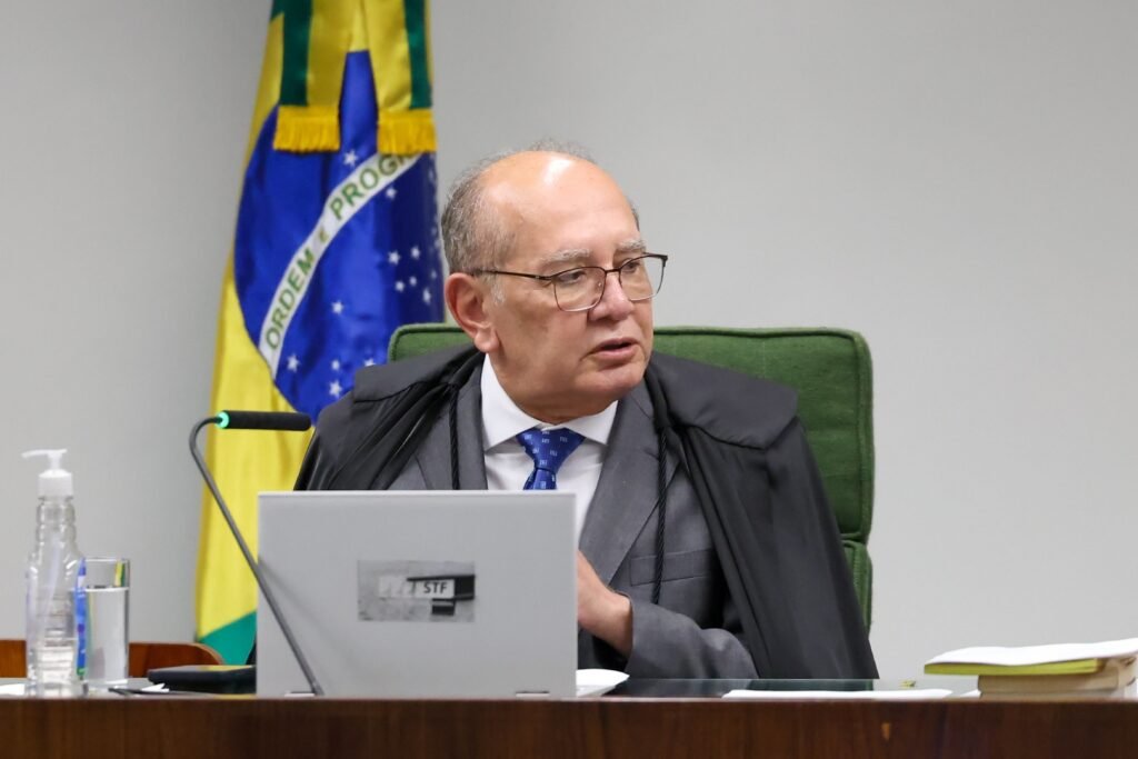 Bastou uma frase para acender um debate que já vinha crescendo em silêncio. Mas por que uma declaração tão direta chamou tanta atenção? Porque ela não surgiu no vazio. Veio no momento em que aumentavam as críticas ao nome escolhido para uma vaga de enorme peso institucional, e justamente por isso cada palavra passou a ser lida como sinal, recado e posicionamento. E o que foi dito de tão forte? A defesa foi objetiva: o indicado “está à altura do cargo”. Só que o impacto não está apenas nessa frase. O que realmente mexe com o cenário é quem decidiu dizê-la e em que contexto ela apareceu, quando a pressão sobre a escolha já ganhava espaço. Mas por que havia tanta pressão? Porque setores da imprensa vinham fazendo críticas ao nome apresentado, classificadas como apressadas e vazias por quem saiu em sua defesa. A reação, então, não foi apenas um elogio. Foi também uma contestação direta à forma como o debate vinha sendo conduzido. E qual foi o argumento usado para rebater essas críticas? A resposta passou pelo currículo. Segundo a defesa feita publicamente, as análises negativas ignoravam uma trajetória marcada por experiência na administração pública e sólida formação acadêmica. Isso muda a discussão? Em parte, sim. Porque tira o foco da impressão imediata e empurra o debate para a qualificação técnica. Mas há um detalhe que quase ninguém percebe: a defesa não se limitou a listar títulos ou funções. Ela destacou também o modo como essa trajetória foi construída. O nome em questão foi associado a atuação técnica, respeito à separação dos Poderes e perfil conciliador. E é justamente aí que a maioria se surpreende, porque o centro da mensagem não foi apenas competência, mas comportamento institucional. Por que isso importa tanto agora? Porque a vaga em disputa não é qualquer posto. Trata-se de um espaço no Supremo Tribunal Federal, aberto após a saída de Luís Roberto Barroso e que estava vago havia mais de quatro meses. Quando uma cadeira desse tamanho fica aberta por tanto tempo, a escolha seguinte naturalmente se torna ainda mais observada. E quem está no centro dessa indicação? Só depois de toda essa tensão o nome aparece com mais nitidez: Jorge Messias, atual advogado-geral da União, indicado pelo presidente Luiz Inácio Lula da Silva para a vaga no STF. A partir daí, a defesa ganha outro peso, porque não se trata apenas de uma opinião sobre alguém do governo, mas sobre um indicado à mais alta Corte do país. Então o que foi usado para sustentar essa defesa? Além da passagem pela AGU, foi lembrado o papel desempenhado na defesa da responsabilização de big techs por conteúdos criminosos nas redes sociais. O que isso revela? Que a argumentação buscou mostrar atuação concreta em temas sensíveis e atuais, conectando experiência administrativa com debates jurídicos de grande impacto. Mas o que acontece depois muda tudo: a decisão não depende apenas da indicação nem da defesa pública. O Senado entra no centro da cena. E foi justamente isso que também apareceu na declaração, com a afirmação de que os senadores saberão avaliar os atributos do indicado. Parece uma frase protocolar? Talvez. Mas, nesse contexto, ela funciona como um deslocamento do embate público para o rito institucional. Então a fala encerra a discussão? Muito pelo contrário. Ela reorganiza o debate. De um lado, críticas ao nome escolhido. De outro, uma defesa que insiste em currículo qualificado, experiência no serviço público, atuação técnica e senso institucional. No meio disso, uma vaga no Supremo, um indicado de Lula e um Senado que ainda terá a palavra decisiva. E qual é o ponto principal no fim de tudo? A declaração de Gilmar Mendes não foi apenas um gesto de apoio. Foi uma tentativa clara de enquadrar Jorge Messias como alguém preparado para o STF, em resposta direta às críticas que cercam sua indicação. Só que a parte mais interessante talvez comece agora, porque quando a defesa pública fica tão explícita, a próxima pergunta deixa de ser apenas se ele tem currículo — e passa a ser como esse currículo será lido quando a avaliação sair das redes e entrar, de fato, no julgamento político e institucional.