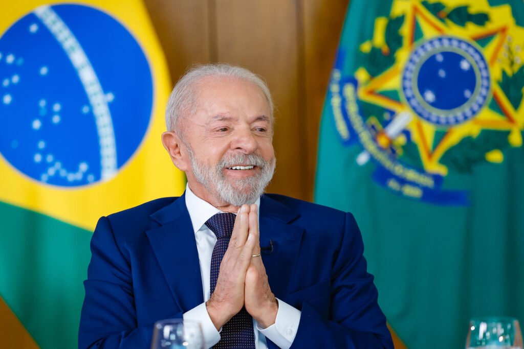 Quando tudo parecia pronto para avançar, o freio veio de onde muita gente não esperava. Mas por que uma votação já prevista simplesmente saiu do trilho? Porque, na véspera da decisão, ficou claro que o texto que tratava do trabalho por aplicativos enfrentava resistência justamente entre quem seria mais afetado por ele: motoristas e entregadores. E o que havia nesse relatório para provocar tanta reação? A proposta criava dois regimes para entregadores. Em um deles, haveria valor fixo de R$ 8,50 por entrega. No outro, o pagamento seria calculado com base nas horas efetivamente trabalhadas. Para os motoristas, o ponto mais sensível foi outro: o texto retirava o piso mínimo de remuneração que aparecia em versões anteriores. Mas isso, por si só, explica o recuo? Explica parte, mas não tudo. O problema maior estava na forma como os trabalhadores enxergaram essas regras. A crítica central era direta: o pagamento continuaria considerando apenas o tempo de execução das corridas ou entregas, e não o período em que o profissional permanece disponível na plataforma esperando chamadas. E por que esse detalhe pesa tanto? Porque é justamente aí que a discussão muda de nível. Para quem trabalha por aplicativo, não basta olhar apenas para o momento em que a corrida começa ou a entrega sai. O tempo de espera também faz parte da rotina, e é nesse ponto que muitos viram o relatório como insuficiente. Então o governo percebeu isso em cima da hora? Foi exatamente esse movimento que levou à mudança de rota. O Planalto identificou a rejeição ao texto e interrompeu o avanço do projeto. A votação do relatório, que estava prevista para a comissão especial da Câmara, foi suspensa. E o que viria depois também mudou: a análise em plenário, marcada para o dia seguinte, acabou descartada. Mas há um detalhe que quase ninguém percebe de imediato: esse adiamento não foi apenas técnico. Ele expôs um impasse político. De um lado, trabalhadores organizavam manifestações em várias capitais, todas contrárias ao relatório. De outro, havia pressão para que o processo legislativo fosse concluído ainda em abril. Quem estava pressionando pela aprovação? Na semana anterior à suspensão, representantes de aplicativos e do setor de alimentação estiveram em Brasília defendendo o texto. A Associação Nacional de Restaurantes argumentou que um preço fixo desconsidera as diferenças entre restaurantes e suas margens. Já o CEO do iFood classificou o projeto como uma oportunidade histórica para ampliar a proteção social de mais de 2 milhões de trabalhadores, embora tenha admitido que o texto estava longe do ideal. Se havia apoio empresarial, por que a proposta não andou? Porque o apoio mais decisivo faltou no momento crucial. E é aqui que a maioria se surpreende: o próprio governo, que iniciou o debate sobre a regulamentação das plataformas digitais no primeiro ano do terceiro mandato de Lula, recuou ao perceber que não havia acordo suficiente para sustentar a votação. E como a Câmara reagiu a isso? O recuo do Planalto gerou desconforto. O presidente da Casa, Hugo Motta, já havia planejado a conclusão do processo legislativo em abril, mas passou a considerar inviável pautar o projeto sem o respaldo do governo. Ao mesmo tempo, o novo líder do governo na Câmara, Paulo Pimenta, resumiu o impasse com uma frase que diz muito: o texto “ainda não está maduro”. Mas então o relatório foi simplesmente descartado? Não. O relator, deputado Augusto Coutinho, defendeu o trabalho feito e afirmou que houve cuidado para não elevar o preço ao consumidor, não onerar a Previdência e não inviabilizar o ambiente de negócios. Só que o que acontece depois muda tudo: quando um texto tenta equilibrar empresas, consumidores e governo, mas não convence os trabalhadores, a base da proposta começa a ceder. E o que isso revela sobre a regulamentação dos aplicativos no Brasil? Revela que o debate continua aberto, mesmo depois de meses de discussão conduzida pelo Ministério do Trabalho e Emprego. Até agora, não houve acordo entre trabalhadores e empresas. E esse é o ponto que ficou mais visível com o adiamento. No fim, a votação sobre o trabalho por aplicativos foi adiada porque o governo percebeu que apoiar o projeto naquele momento significaria avançar sem o aval de quem está nas ruas, nas motos e nos carros. Só que a parte mais importante talvez esteja justamente aí: se o texto ainda não amadureceu, a próxima versão pode reabrir uma disputa ainda maior.