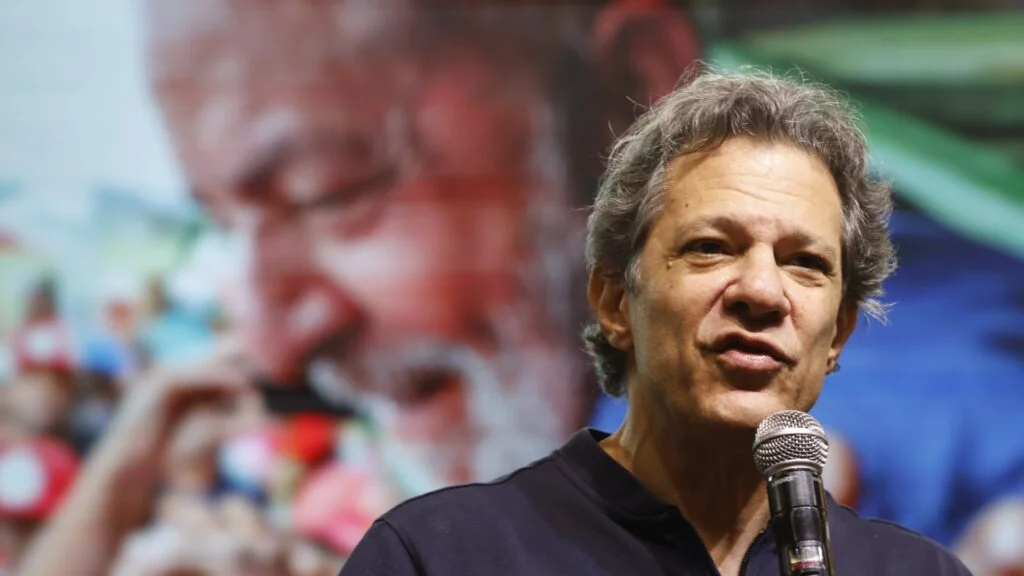 O ataque veio em tom de campanha. O alvo foi a família Bolsonaro. Mas o recado não ficou só nisso. O que Fernando Haddad disse? Neste domingo, 26 de abril de 2026, Haddad afirmou que os Bolsonaros “se vendem como antissistema”. E foi além. Disse que, na prática, a família “há 30 anos faz a pior política da história desse país”. Onde isso aconteceu? A declaração foi feita no 8º Congresso Nacional do PT. O evento ocorreu no Hotel Brasil 21, em Brasília. E não era um encontro qualquer. Ali, o partido reuniu ministros, ex-ministros, congressistas e pré-candidatos. Por que a fala chamou atenção? Porque ela veio em um ambiente de mobilização eleitoral. Haddad é pré-candidato ao governo de São Paulo. E usou o palco partidário para reforçar a linha de confronto com o bolsonarismo. Mas houve outro ponto ainda mais direto. Qual foi? Haddad disse que o PT não pode sequer considerar a hipótese de um “retrocesso” em outubro deste ano. A frase aponta para 2026. E tenta transformar a disputa em um embate entre continuidade e retorno. Retorno de quem? Na fala de Haddad, do campo ligado aos Bolsonaro. Ele também declarou que Lula vai concorrer com o “Bolsonarinho”. A referência foi a Flávio Bolsonaro, do PL. E a escolha do apelido não foi casual. Ela reduz o adversário à condição de herdeiro político. Ao mesmo tempo, tenta colar nele o peso do sobrenome. Mas Haddad parou por aí? Não. Ele afirmou que se trata de uma família que “só trouxe caos para este país”. Com isso, elevou o tom do discurso. E reforçou a estratégia de associar o adversário a desordem e retrocesso. Só que há uma contradição política no centro dessa fala. Qual? O PT tenta se apresentar como solução definitiva. Haddad disse que o partido é “o antídoto, a resposta e a força que não admite parar de avançar”. A mensagem é clara. O partido quer ocupar o lugar de barreira contra o bolsonarismo. E quer fazer isso sem espaço para meio-termo. Por que isso importa? Porque o congresso do PT não discutiu apenas discurso. Durante o encontro, a sigla aprovou um novo manifesto. Com qual objetivo? Ampliar a base para a reeleição do presidente Luiz Inácio Lula da Silva. E, ao mesmo tempo, manter a identidade do partido. Esse detalhe muda a leitura? Muda. A fala de Haddad não aparece isolada. Ela se encaixa em um movimento maior de organização interna e preparação eleitoral. Ou seja, o ataque aos Bolsonaro veio junto com a tentativa de consolidar o discurso do PT para 2026. Quando começou esse encontro? Na sexta-feira, 24 de abril. E se encerrou neste domingo, 26. Ao longo dos dias, o partido reuniu nomes de peso. Isso ajuda a entender o tom adotado? Sim. Num ambiente desse tipo, cada frase tem endereço político. Cada declaração ajuda a marcar posição. E Haddad escolheu marcar posição com confronto direto. O que fica no fim? Fica a tentativa do PT de transformar 2026 em um plebiscito político. De um lado, Lula e a reeleição. Do outro, o nome associado por Haddad ao “retrocesso”. E é justamente aí que está o ponto principal. A fala não foi apenas um ataque aos Bolsonaro. Foi uma peça de campanha. Com ela, Haddad ajudou a desenhar a narrativa que o PT quer impor. A de que só há avanço com o partido. E de que qualquer alternativa representa volta ao caos. Esse foi o centro da mensagem. E foi dito sem rodeios, diante da cúpula petista, em pleno congresso nacional da sigla.