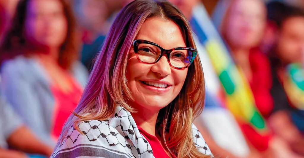 Ela viajou mais do que o próprio presidente. O dado chama atenção por si só, mas o que ele revela vai além da curiosidade sobre deslocamentos oficiais. Em um ano de divulgação pública da agenda da primeira-dama Janja, o Palácio do Planalto registrou compromissos em 12 países e em 32 cidades brasileiras. A exposição dessas agendas começou há 12 meses, após orientação da Advocacia-Geral da União sobre a atuação da mulher do presidente Lula. A pergunta que surge é simples: qual foi o tamanho dessa presença? Os números ajudam a responder. Nesse período, Janja teve compromissos no exterior na Colômbia, China, Coreia do Sul, Espanha, Estados Unidos, França, Itália, Indonésia, Malásia, Rússia, Uruguai e Vaticano. Em alguns casos, os destinos se repetiram, como Estados Unidos, França e Vaticano. No Brasil, ela deixou Brasília para agendas em 32 municípios distribuídos por 13 Estados. Mas o ponto que mais chama atenção aparece quando se observa apenas 2026. Janja passou mais tempo fora do país do que Lula. Segundo levantamento do Poder360, foram 20 dias no exterior, em quatro viagens para seis destinos. No mesmo período, o presidente ficou 16 dias fora do Brasil. A diferença é pequena no calendário, mas grande no simbolismo político, porque expõe o peso crescente da atuação internacional da primeira-dama dentro de um governo que já é marcado por forte presença pessoal e por agendas paralelas. Isso aconteceu só neste ano? Não. Desde o início do mandato, em 2023, Janja acumula 177 dias no exterior. São 23 dias a mais do que Lula, que soma 154. Ao todo, a primeira-dama visitou 38 países em 37 viagens. Já o presidente passou por 41 nações em 44 viagens presidenciais. O que Janja fez nessas agendas? Em 2025, ela acompanhou Lula em compromissos na Ásia e na Europa. Também realizou uma viagem solo de cinco dias aos Estados Unidos, em março, para um evento da Organização das Nações Unidas. Mais recentemente, Lula e Janja encerraram uma viagem de seis dias por Espanha, Alemanha e Portugal. É nesse trecho que aparece uma virada importante. Enquanto Lula usou a agenda em Hannover para pedir que a Europa abandone a “resistência ideológica” contra os biocombustíveis brasileiros e, em Lisboa, ironizou Donald Trump ao dizer que o republicano deveria receber o Nobel da Paz para encerrar guerras, Janja cumpriu agenda própria em território espanhol antes de se encontrar com o presidente em Barcelona. E qual foi o foco dessa agenda independente? Em Valência, a primeira-dama participou de debate sobre “ecofeminismo” e depois criticou a atuação das big techs em um painel sobre acesso global à Justiça. Também visitou o sistema espanhol de acompanhamento de casos de violência de gênero ao lado de ministros locais. Por que isso importa? Porque a divulgação oficial da agenda, iniciada por orientação da AGU, acabou oferecendo um retrato mais claro da dimensão política e institucional da atuação da primeira-dama. O que antes poderia parecer presença acessória passou a aparecer como rotina estruturada, com compromissos próprios, deslocamentos frequentes e participação em temas ideológicos e internacionais sensíveis. Ao mesmo tempo, os números de Lula ajudam a compor o contraste. O presidente visitou oito países em 2026. Desde que assumiu, passou 154 dias fora do Brasil. O ano de 2023 foi o de maior ausência, com 62 dias no exterior. Em 2024, a frequência caiu por causa de uma cirurgia na cabeça. Em 2025, voltou a subir, com 50 dias fora do país. Na viagem mais recente, o governo fechou 15 atos de cooperação com a Espanha e outros dez acordos com a Alemanha. Os compromissos envolveram temas como inteligência artificial, defesa e bioeconomia. Ainda assim, o dado que mais se impõe no balanço não é apenas o volume de acordos nem o roteiro presidencial. É outro. Em um ano de agendas tornadas públicas, Janja não apenas ampliou sua presença institucional. Ela circulou por 12 países e 32 cidades brasileiras. E, em 2026, ficou mais tempo no exterior do que o próprio chefe de Estado. Para um governo que costuma concentrar poder, imagem e discurso em torno de Lula e do PT, o número revela uma contradição difícil de ignorar: a primeira-dama deixou de ser apenas acompanhante de viagem e passou a ocupar, na prática, um espaço político cada vez mais visível.