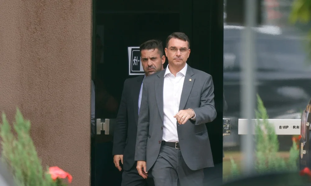 A comemoração veio antes mesmo de qualquer cautela política. No dia em que completou 45 anos, o senador Flávio Bolsonaro celebrou a derrubada do veto de Lula ao chamado PL da Dosimetria e transformou a votação em um gesto de expectativa pessoal e política. Disse que não poderia haver presente melhor de aniversário e voltou a falar no desejo de ser eleito presidente da República para subir a rampa do Planalto ao lado do pai, o ex-presidente Jair Bolsonaro. Mas o que exatamente mudou com essa decisão do Congresso? A resposta está no coração do projeto. O texto reduz penas aplicadas a condenados por tentativa de golpe de Estado e por envolvimento nos atos de 8 de janeiro de 2023. Na prática, altera a forma de cálculo das punições quando os crimes de tentativa contra o Estado Democrático de Direito e de golpe de Estado são praticados no mesmo contexto. Em vez da soma das penas, passa a valer a pena mais grave. Por que isso provocou tanta reação? Porque a mudança atinge diretamente condenados pelos fatos de 8 de janeiro e também beneficia Jair Bolsonaro com a diminuição de sua pena, segundo o conteúdo informado. Foi justamente por isso que a votação ganhou peso político imediato e virou mais uma derrota para o governo Lula. Os números mostram o tamanho do revés. Na Câmara, 318 deputados votaram pela derrubada do veto, contra 144. No Senado, foram 49 votos favoráveis e 24 contrários. O resultado expôs mais uma vez a dificuldade do governo em sustentar sua posição no Congresso, e isso ocorreu um dia depois de outra derrota relevante: a rejeição, pelo Senado, do indicado de Lula, Jorge Messias, para uma vaga no STF. Lula havia vetado integralmente o projeto em 8 de janeiro, na data que marcava três anos dos atos de 2023. A justificativa do governo foi a de que reduzir a resposta penal para crimes contra o Estado Democrático de Direito poderia estimular novas infrações e representar retrocesso no processo de redemocratização. Também alegou possível afronta a princípios como proporcionalidade, isonomia e impessoalidade. Só que a história não parou aí. Antes da votação, surgiu um ponto que poderia embaralhar tudo. O presidente do Senado, Davi Alcolumbre, fez uma manobra para retirar trechos do projeto da pauta. Por quê? Porque havia conflito entre o PL da Dosimetria e a Lei Antifacção, aprovada depois pelo próprio Congresso. A contradição atingia pontos da Lei de Execução Penal ligados à progressão de regime para crimes como feminicídio, formação de milícia privada, crimes hediondos e liderança de facções criminosas. Isso significava afrouxamento geral das penas? Não. E esse foi o detalhe que reativou a disputa no plenário. Alcolumbre declarou a “prejudicialidade” dos trechos conflitantes justamente para evitar que a derrubada do veto fosse interpretada como um passo atrás no combate ao crime organizado e ao feminicídio. Segundo ele, a intenção original do projeto não era mexer nesse rigor específico. A saída foi usar o regimento para preservar a parte central da proposta e afastar a colisão com a lei mais recente. O projeto já havia sido aprovado em dezembro de 2025. Na época, passou pela Câmara por 291 votos a 148 e depois pelo Senado por 48 a 25. O texto original previa anistia a todos os envolvidos nos atos de 8 de janeiro e aos acusados dos quatro grupos relacionados à tentativa de golpe julgados pelo STF. Esse artigo, porém, foi retirado. Então qual é o ponto principal, afinal? Perto do fim da disputa legislativa, ficou claro que o Congresso decidiu manter uma mudança objetiva na dosimetria das penas, sem restaurar a anistia ampla que constava da versão inicial. O efeito concreto é reduzir o tempo de punição e também encurtar o prazo para progressão de regime, beneficiando os condenados pela tentativa de golpe de Estado, inclusive os do grupo principal, que receberam penas entre 16 e 24 anos em regime fechado pela 1ª Turma do STF. Foi esse desfecho que levou Flávio Bolsonaro a falar novamente em futuro eleitoral e em “subir a rampa” com o pai. A frase, mais do que celebração pessoal, veio embalada por um fato político maior: a derrubada de um veto presidencial, a redução de penas em um tema sensível e mais um sinal de desgaste do governo Lula diante do Congresso.