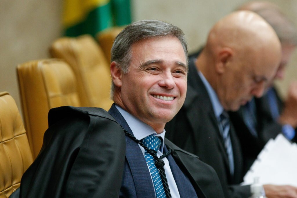Em meio a uma crise que pressiona o **Supremo Tribunal Federal**, André Mendonça escolheu uma frase direta para marcar posição: **um bom magistrado não privilegia amigos nem persegue inimigos**. Onde ele disse isso, e por que a declaração ganhou tanto peso? A fala foi feita na noite de segunda-feira, 6, durante uma homenagem da **Assembleia Legislativa de São Paulo**, que concedeu ao ministro o **Colar da Honra ao Mérito Legislativo**. Mas o que exatamente Mendonça afirmou naquele discurso? Ao receber a homenagem, ele disse que um bom juiz deve ser **imparcial**, **íntegro**, **responsável** e comprometido em **buscar a Justiça**. Também declarou que o único interesse de um magistrado deve ser **“fazer o que é certo”**. Em seguida, detalhou o que entende por imparcialidade: olhar para as pessoas de modo igualitário, considerar os interesses envolvidos de forma equânime, **não privilegiar amigos** e **não perseguir inimigos**. Foi nesse contexto que assumiu publicamente esse compromisso na chamada **Casa do povo de São Paulo**. Por que essa fala repercutiu além da cerimônia? Porque ela ocorreu no momento em que o Supremo enfrenta desdobramentos do caso envolvendo o **Banco Master**. Mendonça é relator dos inquéritos do banco e também dos descontos irregulares no **INSS**, e afirmou que seguirá esses princípios no tribunal. A declaração, portanto, não apareceu de forma abstrata. Ela foi feita quando o debate sobre conduta, credibilidade e independência dos ministros já estava no centro das atenções. E qual é o pano de fundo dessa crise? O ministro **Dias Toffoli** deixou a relatoria do inquérito após a **Polícia Federal** encontrar menções a ele no celular de **Daniel Vorcaro**, dono do Banco Master. Ao mesmo tempo, o escritório da família do ministro **Alexandre de Moraes** firmou um contrato de **R$ 129 milhões** com o banco por três anos. Moraes e Toffoli **negam qualquer irregularidade**, mas a situação levou o presidente do STF, **Edson Fachin**, a anunciar um **Código de Ética** para os integrantes da Corte. Mendonça tratou apenas de imparcialidade? Não. Ele também falou sobre a relação entre magistratura e confiança pública. Disse que juízes não estão **imunes a incompreensões**, mas precisam estar imunes a ações que comprometam, de forma substancial, voluntária e consciente, a **credibilidade** que a sociedade espera de um bom magistrado. A fala reforçou a ideia de que a função exige não só independência, mas também preservação da confiança institucional. Quem esteve ao lado dele nesse evento? A cerimônia reuniu nomes de peso da política. O governador **Tarcísio de Freitas** afirmou que o ministro representa uma **“esperança no deserto”** e atua com **imparcialidade, discrição e firmeza**. O deputado estadual **Oseias de Madureira**, autor da homenagem, disse que a atuação de Mendonça na Corte representa algo mais profundo, por ser, segundo ele, a voz de uma parcela da sociedade que valoriza **a família**, **a liberdade religiosa** e princípios que considera fundamentais. Já o presidente da Alesp, **André do Prado**, declarou que a trajetória do ministro **honra o Brasil** e mostra que o serviço público pode ser exercido com **equilíbrio**. Houve mais manifestações? Sim. O prefeito de São Paulo, **Ricardo Nunes**, disse se considerar **amigo** de Mendonça e o classificou como **um grande exemplo**. A presença de autoridades, porém, não se limitou a elogios. Um dos nomes que mais chamaram atenção foi o do advogado-geral da União, **Jorge Messias**, indicado pelo presidente **Luiz Inácio Lula da Silva** ao STF. Ele participou da homenagem, mas não discursou. E como Mendonça se dirigiu a Messias? Com uma fala pública de apoio à indicação. O ministro disse que era uma honra ter o AGU presente e recordou a importância da **Advocacia-Geral da União** na trajetória de ambos. Depois, afirmou: **“Nossas carreiras na AGU foram grandes divisores de águas para as nossas correspondentes trajetórias e faço votos que, em breve, você possa deixar a AGU por um motivo de estar comigo no Supremo Tribunal Federal”**. Quem mais destacou essa presença? O deputado federal **Cezinha de Madureira**, da bancada evangélica, afirmou que Messias **“fez questão”** de comparecer à homenagem. Ele próprio havia participado, em outubro do ano passado, de uma reunião com Lula e Messias no **Palácio do Planalto**, pouco mais de um mês antes da indicação do AGU ao Supremo. Mendonça, pastor auxiliar da **Igreja Presbiteriana de Pinheiros**, e Messias, membro da **Igreja Batista Cristã de Brasília**, estiveram assim no mesmo evento em que a frase mais forte da noite foi dita por inteiro: **“Imparcialidade é olhar para as pessoas de modo igualitário, considerar os interesses envolvidos de forma equânime, não privilegiar amigos, não perseguir inimigos. Esse é um compromisso que eu faço na Casa do povo de São Paulo.”**