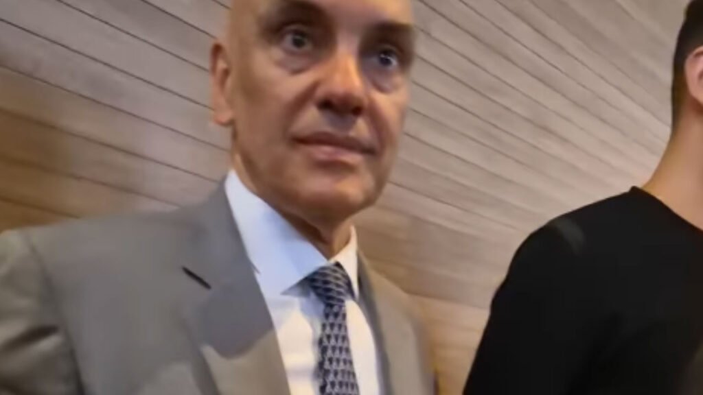 Ele falou sobre democracia, mas foi justamente uma pergunta sobre democracia que fez o silêncio tomar conta da cena. Como isso aconteceu? Em um ambiente que, em tese, existe para debate, reflexão e confronto de ideias, a expectativa natural seria de resposta, esclarecimento, talvez até de aprofundamento. Mas o que veio foi outra coisa: uma interrupção seca, breve, suficiente para transformar um momento comum em algo muito mais simbólico. Que momento foi esse? Tudo começou durante uma participação pública em uma palestra com foco institucional. O tema parecia previsível, quase protocolar, girando em torno de eleições, regras do jogo democrático e funcionamento das instituições. Até aí, nada fora do esperado. Mas bastou uma abordagem direta para o clima mudar. E qual foi a pergunta? A questão levantada tratava do cenário democrático diante de escândalos recentes. Não era uma pergunta fora do assunto. Pelo contrário: tocava exatamente no centro do tema que estava sendo discutido. E é justamente por isso que o episódio chama atenção. Se o assunto era democracia, por que evitar comentar uma dúvida ligada à própria democracia? A resposta veio? Não da forma que muitos imaginavam. Antes de qualquer desenvolvimento, houve a identificação da interlocutora como jornalista. Foi nesse ponto que a conversa praticamente terminou. A partir daí, a posição foi objetiva: não haveria declaração à imprensa naquele momento. Mas isso encerra o caso? Na prática, encerrou a tentativa de interação. No entanto, é aí que a maioria se surpreende: o silêncio, em situações assim, muitas vezes fala mais do que uma resposta longa. Quando alguém participa de um evento sobre instituições democráticas e, logo depois, evita comentar um questionamento público sobre esse mesmo tema, o contraste se torna inevitável. Onde isso aconteceu? Só agora o cenário fica completo. O episódio ocorreu na Faculdade de Direito da USP, durante um evento realizado na sexta-feira, 10 de abril. A palestra tinha como tema “Eleições e democracia”. E esse detalhe muda a leitura de tudo, porque não se tratava de uma aparição casual, nem de uma abordagem em corredor sem relação com o assunto. O contexto era precisamente o debate institucional. Quem era a figura central desse momento? O ministro Alexandre de Moraes, do Supremo Tribunal Federal. Durante sua exposição, ele tratou de aspectos institucionais ligados ao processo eleitoral e à democracia no país. Ou seja, o conteúdo apresentado estava diretamente conectado ao tipo de pergunta que surgiu depois. Então por que a recusa repercute tanto? Porque não foi apenas uma negativa qualquer. O que chama atenção é a distância entre o discurso apresentado no ambiente acadêmico e a decisão de não comentar questionamentos externos logo em seguida. Mas há um ponto que quase passa despercebido: a recusa não veio antes da pergunta existir. Ela veio depois da identificação da pessoa que perguntava como jornalista. E por que isso importa? Porque esse detalhe redefine a cena. Não se tratou simplesmente de falta de tempo ou de encerramento espontâneo da conversa. O que aconteceu depois altera a percepção do episódio: ao saber que se tratava de imprensa, o ministro afirmou que não concederia declarações naquele momento. E foi isso que encerrou a interação. Isso contradiz o conteúdo da palestra? Formalmente, não é possível afirmar mais do que os fatos mostram. O que se pode dizer, com base no que foi relatado, é que houve um contraste claro entre a exposição sobre democracia e a recusa em responder a uma pergunta sobre democracia feita por uma jornalista. E esse contraste, por si só, sustenta a repercussão. Mas o que fica desse episódio? Fica uma imagem difícil de ignorar: um evento sobre “Eleições e democracia”, uma pergunta diretamente ligada ao tema, uma identificação profissional e, em seguida, o silêncio. O ponto principal não está apenas na ausência de resposta, mas no que essa ausência projeta em um ambiente que simboliza debate público. E o que isso revela? Talvez menos sobre uma frase que não foi dita e mais sobre o peso de escolher não dizê-la. Porque, às vezes, o momento mais revelador de um discurso não está no palco, mas no instante exato em que alguém decide não continuar falando.