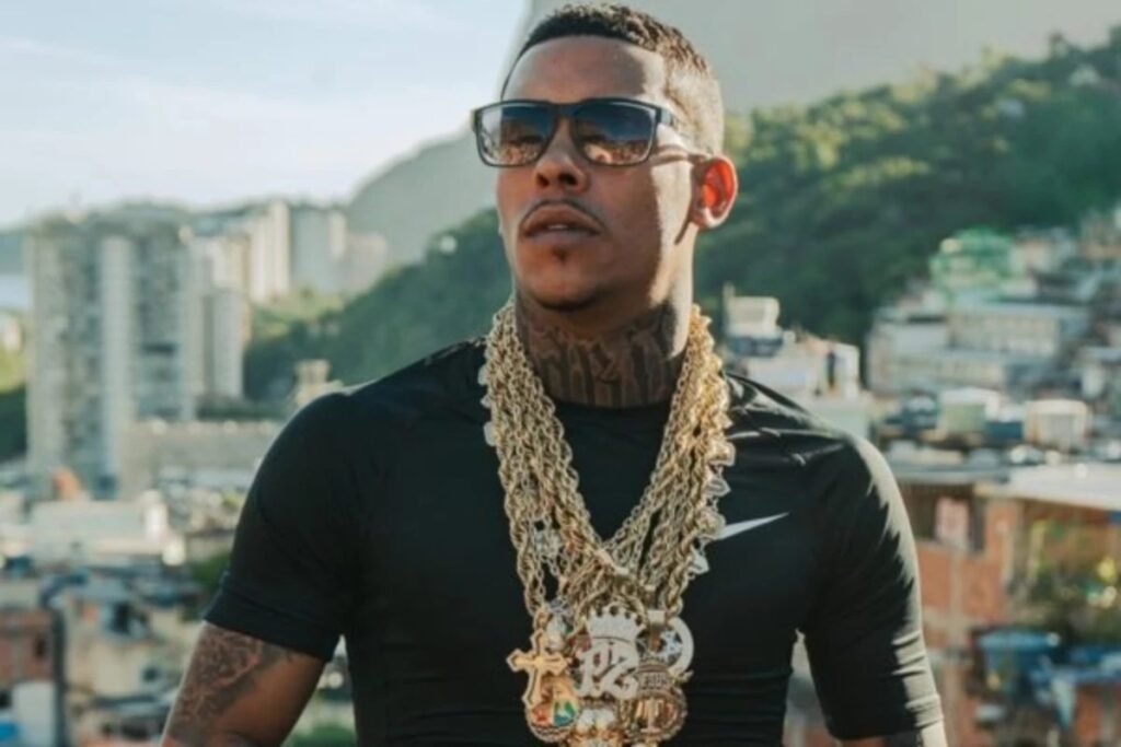 Ela diz que espera há anos por uma resposta que poderia mudar tudo. Mas resposta sobre o quê, exatamente? Sobre a paternidade de uma criança. Uma mulher identificada como Bia Nascimento afirma ter tido um relacionamento com MC Poze do Rodo antes de o cantor alcançar a fama e sustenta que dessa relação nasceu um filho. A questão, porém, não parou na alegação. Ela afirma que tentou resolver a situação, buscou contato e ouviu uma negativa. E o que aconteceu quando ela procurou o artista? Segundo o relato publicado por ela nas redes sociais, ao conseguir contato com o funkeiro, recebeu a informação de que a criança não seria filha dele. Diante disso, ainda de acordo com a versão apresentada por Bia, a orientação teria sido direta: procurar a Justiça. E foi justamente aí que a história deixou de ser apenas pessoal e passou a ganhar outro peso. Se ela entrou na Justiça, por que o caso voltou a repercutir agora? Porque Bia decidiu expor publicamente a frustração com a demora. Em desabafos publicados nos stories, ela afirmou que o processo se arrasta há anos sem solução e cobrou andamento. Disse que não quer fama nem visibilidade com a exposição do caso. O objetivo, segundo ela, é um só: a realização do exame de DNA. Mas se o exame é o centro de tudo, ele já foi marcado alguma vez? Sim, e é aqui que muita gente para para prestar mais atenção. Houve uma tentativa de realização do teste por meio da Defensoria Pública. Um suposto documento compartilhado nas redes indica que Bia esteve em um laboratório do Rio de Janeiro para a coleta de material biológico e genético. O ponto que reacendeu a discussão foi outro: segundo a alegação dela, o cantor não compareceu na data marcada. Isso significa que o exame não aconteceu? Pelo que foi relatado por Bia, não. E esse detalhe muda o rumo da história, porque sem o teste, a principal resposta continua suspensa. Foi justamente essa ausência, apontada por ela, que ampliou a sensação de impasse e fez surgir uma nova camada de dúvidas sobre o andamento do processo. Mas por que, depois de tanto tempo, ainda não houve definição? Essa é a pergunta que a própria Bia passou a fazer em público. Em seus relatos, ela questionou a falta de movimentação no caso e citou diretamente a 2ª Vara do Fórum de Campo Grande, no Rio. Classificou a situação como estranha e disse não entender por que anos e meses se passaram sem solução concreta. E há mais dúvidas além da demora? Sim, e talvez sejam as que mais chamam atenção. Bia levantou questionamentos sobre a tentativa de localização do cantor. Em tom de indignação, perguntou se a Justiça não o encontra ou se simplesmente não está procurando. Foi além: sugeriu a possibilidade de que procurem, achem e algo mude no caminho. É nesse ponto que a narrativa ganha ainda mais tensão, porque a dúvida deixa de ser apenas sobre paternidade e passa a envolver também o funcionamento do processo. Mas quem é o homem citado nessa disputa? Só agora o contexto fica completo. Trata-se de MC Poze do Rodo, nome artístico de Marlon Brandon Coelho Couto Silva, um dos nomes conhecidos do funk. Atualmente, ele é pai de cinco filhos reconhecidos publicamente: Júlia, Miguel e Laura, do relacionamento com Vivianne Noronha; Jade, filha de Isabelly Pereira; e Manuela, fruto da relação com Myllena Rocha. Então o que Bia quer, afinal? Segundo o que escreveu, não é exposição, nem fama, nem disputa pública por atenção. O que ela cobra é algo objetivo: que o exame de DNA seja feito e que o processo avance. A pergunta final que ela deixou no ar resume tudo: haverá uma nova data para a realização do teste? É justamente essa pergunta que mantém o caso em aberto. Porque, no fim, toda a repercussão gira em torno de uma única ausência: a da resposta definitiva. E quando ela não vem, cada nova publicação não encerra a história — apenas empurra o leitor para a próxima dúvida.