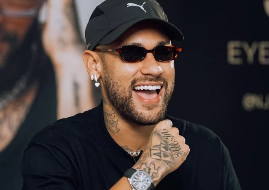 Como Neymar revolucionou o live commerce no Brasil? Neymar Júnior estreou no TikTok com a NJR Eyewear, atingindo o topo da moda no país. A live acumulou 10,7 milhões de impressões e faturou mais de R$ 200 mil. Qual foi o impacto financeiro da live de Neymar? Em menos de uma hora, a live gerou R$ 135 mil, ultrapassando R$ 200 mil ao final. Foi o maior ticket médio de vendas em lives de moda no Brasil. Quais são as linhas de óculos da NJR Eyewear? A coleção de estreia inclui as linhas Origins, Icons e Legends, cada uma com uma narrativa ligada à trajetória de Neymar, diferenciando preço e identidade. Como a NJR Eyewear se posiciona no mercado? A marca busca dialogar com grifes internacionais, mantendo um apelo acessível ao público brasileiro, indo além de produtos licenciados tradicionais. Quais são os planos futuros da NJR Eyewear? A marca planeja expandir para óculos de grau, modelos esportivos e lojas físicas, consolidando-se como um negócio de lifestyle. Por que o live commerce atrai tantas marcas? A combinação de entretenimento, interação em tempo real e compra imediata oferece uma experiência única, ainda não replicada por vitrines físicas ou e-commerce tradicional.