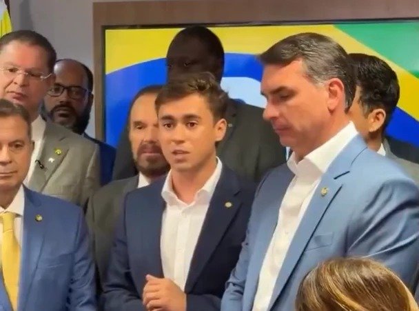 Bastou uma frase para acender um recado político que vai muito além de um encontro público: **“Somos um time”**. Mas por que essa declaração chamou tanta atenção agora? Porque ela surge justamente depois de um momento de **atrito interno**, quando muitos já começavam a se perguntar se a direita entraria em campo dividida. E quando uma fala dessas aparece no timing certo, a dúvida muda de lugar: foi apenas um gesto de cordialidade ou um movimento para conter uma crise maior? A resposta começa a aparecer no tom adotado. Ao lado de **Flávio Bolsonaro**, **Nikolas Ferreira** não falou apenas em apoio pessoal. Ele reforçou que está no **“mesmo time”**, com **“o mesmo inimigo”**, e deixou claro que o objetivo seria **vencer o PT** e enfrentar **Lula** e a esquerda. Só que isso abre outra questão: por que foi necessário reafirmar algo que, em tese, já deveria estar subentendido? Porque havia ruído. E esse é o ponto que muda a leitura de tudo. Nos bastidores recentes, o nome de Nikolas passou a circular no centro de uma tensão com **Eduardo Bolsonaro**. O motivo? Uma sequência de publicações nas redes que acabou sendo interpretada como sinal de desalinhamento. Mas será que foi só uma divergência digital ou algo mais profundo? O episódio começou quando **Eduardo** criticou o dono do perfil **Space Liberdade**, **Keven Oliveira**, após ele declarar que não votaria em **Flávio Bolsonaro** no primeiro turno. No mesmo dia, Nikolas compartilhou uma publicação do perfil. Isso já bastou para irritar o ex-deputado. Só que a situação não parou aí. E é aqui que muita gente se surpreende. A irritação aumentou depois que Nikolas respondeu com um **“kkk”** a uma postagem do cientista político **Silvio Grimaldo**, que dizia que o conteúdo compartilhado por ele era uma crítica a Lula e uma defesa do ex-presidente **Jair Bolsonaro**. O gesto, aparentemente simples, teve efeito político imediato. Eduardo reagiu com críticas mais duras e expôs publicamente a mágoa. Mas o que exatamente Eduardo disse para elevar tanto a temperatura? Ele afirmou que demorou a acreditar que Nikolas estaria usando o algoritmo das redes para dar visibilidade a pessoas que desejariam o mal de seu pai, comemorariam sua prisão e atacariam sua família. Também escreveu que viu com tristeza Nikolas agir contra quem acreditou e o apoiou quando ele ainda era “um assessor desconhecido”. A partir daí, a dúvida ficou inevitável: haveria rompimento? É justamente nesse cenário que a fala de Nikolas ao lado de Flávio ganha peso. Porque ela não aparece isolada. Ela funciona como uma resposta política a um ambiente de desgaste. Ao declarar que **“todas as nossas candidaturas”** são para servir a Flávio e ajudá-lo a derrotar o PT, Nikolas não apenas sinaliza apoio. Ele reposiciona publicamente sua lealdade dentro de uma disputa que já começava a produzir interpretações perigosas. Mas há um detalhe que quase ninguém percebe de imediato: essa reafirmação não aconteceu em qualquer lugar. A fala ocorreu durante o lançamento da **pré-candidatura de Domingos Sávio ao Senado**, em Brasília. E isso importa porque o palco amplia o recado. Não era uma postagem solta, nem uma resposta improvisada. Era um evento político, com plateia, contexto e mensagem calculada. E o que Flávio fez diante desse cenário? Também se moveu. Em vídeo, o senador pediu **“racionalidade”** e **união** entre lideranças da direita. Sem citar diretamente nem o irmão nem Nikolas, afirmou que divergências e mágoas deveriam ser deixadas de lado em nome de um objetivo comum. Disse ainda que é angustiante ver lideranças do mesmo lado se digladiando enquanto há “um país para resgatar” e que, nesse tipo de confusão, **“todo mundo sai perdendo”**. Então o encontro resolve tudo? Não exatamente. O que acontece depois é o que realmente pesa. A imagem de união existe, a declaração foi dada, o apoio foi reafirmado e o discurso de convergência foi colocado sobre a mesa. Mas o fato de isso ter precisado ser dito com tanta ênfase mostra que a tensão anterior deixou marcas. No fim, o ponto principal é esse: **Nikolas Ferreira escolheu aparecer ao lado de Flávio Bolsonaro e reafirmar publicamente que estão do mesmo lado**, depois de um embate que envolveu **Eduardo Bolsonaro** e expôs fissuras. A frase **“somos um time”** não foi apenas simbólica. Foi uma tentativa clara de reorganizar a narrativa. Só que, quando a união precisa ser reafirmada em voz alta, sempre fica no ar a pergunta que ainda não foi totalmente respondida: isso encerra a crise ou apenas adia o próximo capítulo?