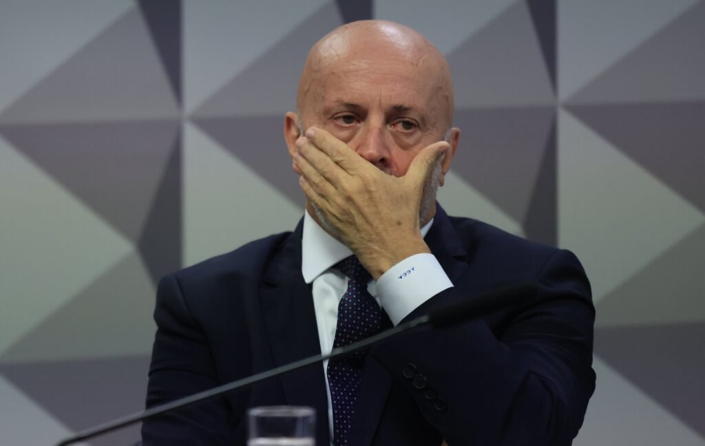 Uma acusação de **omissão** levou o caso do **“Careca do INSS”** a um novo patamar — e agora a cobrança mira diretamente o governo Lula no **TCU**. Mas o que motivou essa ofensiva? A bancada do **Novo no Congresso** apresentou uma representação ao **Tribunal de Contas da União** contra o governo federal por suposta falta de ação na recuperação de recursos desviados no esquema de fraudes contra aposentados do **INSS**. O alvo da iniciativa são a **Advocacia-Geral da União**, a **AGU**, e o **Ministério da Justiça**. Por que esses órgãos foram citados? Porque, segundo os parlamentares, eles deixaram de adotar medidas concretas para **bloquear** e **repatriar** valores ligados ao operador conhecido como **“Careca do INSS”**, mesmo após solicitações formais feitas no âmbito da **CPMI do INSS**. E que valores são esses? De acordo com o documento apresentado ao TCU, a offshore **Camilo & Antunes Limited**, sediada nas **Ilhas Virgens Britânicas**, teria sido usada para a internacionalização do esquema e para a ocultação de patrimônio ilícito. As investigações apontaram que essa estrutura funcionava como **interposta pessoa jurídica**, dificultando o rastreamento dos recursos e permitindo a integração do dinheiro ao sistema formal. Houve movimentação patrimonial identificada? Sim. Em um intervalo de apenas **três meses**, a empresa teria sido usada para adquirir **quatro imóveis no Brasil**, em operações que somaram cerca de **R$ 11 milhões**. E o que a CPMI pediu exatamente? Durante os trabalhos da comissão, foram aprovados requerimentos para que o **Ministério da Justiça**, por meio do **Departamento de Recuperação de Ativos e Cooperação Jurídica Internacional**, o **DRCI**, formalizasse pedidos de **cooperação internacional** para a quebra de sigilo da offshore. Ao mesmo tempo, a **AGU** foi acionada para adotar medidas judiciais de **bloqueio de ativos no exterior**. Essas providências avançaram? Segundo os congressistas, não. A representação afirma que o **Ministério da Justiça** não conseguiu efetivar a cooperação jurídica internacional e manteve sem resposta o pedido de acesso a dados financeiros da offshore. Já a **AGU**, embora tenha reconhecido a viabilidade jurídica de medidas para bloqueio de bens, condicionou sua atuação a etapas prévias e não tomou providências imediatas para garantir a constrição patrimonial dos ativos. Quem sustenta essa crítica de forma mais direta? A deputada **Adriana Ventura**, do **Novo-SP**, afirmou que “**o governo Lula foi omisso**”. Segundo ela, o governo “se recusou a recuperar o dinheiro roubado dos aposentados no exterior”. A parlamentar também declarou que o Ministério da Justiça alegou falta de número de conta, mesmo com provas da existência da empresa e de patrimônio superior a **R$ 11,5 milhões em imóveis**. Sobre a AGU, disse que o órgão afirmou que não valia a pena contratar advogado. Quem mais assinou a representação? Além de **Adriana Ventura**, o pedido ao TCU foi assinado por **Gilson Marques**, **Marcel van Hattem**, **Luiz Lima** e pelo senador **Eduardo Girão**. A iniciativa veio depois das revelações da **CPMI** sobre descontos indevidos aplicados a beneficiários da **Previdência**. Por que a discussão ganhou peso maior? Porque, segundo os parlamentares, a suposta omissão pode ter impacto direto sobre o **erário**. O governo federal autorizou a abertura de **crédito extraordinário de R$ 3,3 bilhões** para ressarcir aposentados prejudicados, transferindo o custo do esquema para os cofres públicos. E qual é o argumento central nesse ponto? O próprio documento afirma que houve mobilização de recursos públicos para cobrir prejuízos causados por terceiros. Por isso, na visão dos autores da representação, a atuação estatal para recompor esses valores se torna obrigatória. Há base jurídica para essa cobrança? A peça apresentada ao **TCU** sustenta que a jurisprudência da Corte considera a **omissão administrativa**, especialmente quando resulta em prejuízo ao interesse público, como passível de sanção. O texto também cita precedentes que classificam a demora injustificada na adoção de medidas como violação ao **princípio da eficiência**. E o que os parlamentares pedem agora? Eles solicitaram uma **medida cautelar** para obrigar a **AGU** e o **Ministério da Justiça** a adotar providências imediatas de **rastreamento**, **bloqueio** e **recuperação dos ativos** vinculados à offshore **Camilo & Antunes Limited**, sediada nas **Ilhas Virgens Britânicas**. Também pediram a fixação de prazo para apresentação de um **plano de ação detalhado**, além do reconhecimento formal da omissão dos órgãos e da eventual responsabilização dos agentes envolvidos.