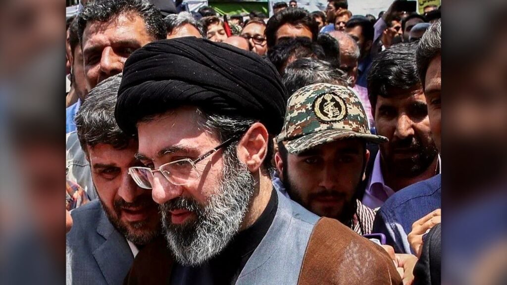 Ele assumiu o posto mais sensível do Irã sem aparecer em público, e agora uma pergunta domina tudo: o que realmente aconteceu com o novo líder supremo? A resposta que circula é grave, mas ainda cercada de sombras. Segundo informações relatadas pela Reuters, Mojtaba Khamenei estaria se recuperando de ferimentos severos sofridos no ataque aéreo que matou seu pai, Ali Khamenei, no início da guerra. Entre os danos citados por fontes próximas ao seu círculo, está algo que muda completamente a percepção sobre sua condição: o rosto teria ficado desfigurado. Mas se esse é o quadro, como ele continua no centro do poder? É justamente aí que a história começa a ficar mais tensa. Mesmo ferido, Mojtaba seguiria participando das decisões do governo. De acordo com essas fontes, ele continua envolvido em temas decisivos, como a condução da guerra e as negociações com os Estados Unidos. Só que há um detalhe que quase ninguém percebe: essa atuação estaria acontecendo sem presença física, por meio de conferências de áudio. E isso levanta outra dúvida inevitável: por que alguém tão central permanece fora de vista? A ausência pública não é um detalhe menor. Desde que foi escolhido como líder supremo do Irã, Mojtaba Khamenei não fez aparições públicas. Isso, por si só, já alimenta especulações. Mas o que sustenta essas informações? A Reuters afirma que ouviu fontes próximas ao círculo do líder, embora também deixe claro que não conseguiu verificar os relatos de forma independente. E é aqui que muita gente se surpreende: mesmo sem confirmação autônoma, outros sinais começaram a apontar na mesma direção. Um desses sinais veio de dentro do próprio ambiente político iraniano. Yusef Pezeshkian, filho do presidente Masoud Pezeshkian e assessor do governo, confirmou que Mojtaba foi ferido no início da ofensiva militar de Estados Unidos e Israel. Em mensagem no Telegram, ele disse ter buscado informações com pessoas em contato com Mojtaba e afirmou que, “pela graça de Deus”, ele estaria bem e sem problemas. Mas se ele está bem, por que o silêncio visual continua? E por que os relatos sobre a gravidade dos ferimentos não desaparecem? A resposta pode estar no que foi publicado por outros veículos. O New York Times informou, citando funcionários do regime iraniano, que Mojtaba sofreu ferimentos inclusive nas pernas no primeiro dia do ataque realizado por Israel e pelos Estados Unidos. O jornal também afirmou que ele está abrigado em um local de alta segurança, com comunicação limitada. O que acontece depois muda tudo, porque essa combinação de isolamento, lesões e ausência pública reforça a imagem de um líder ativo, mas inacessível. E quando um líder governa sem ser visto, a dúvida cresce ainda mais. Mas há outro ponto que amplia o peso dessa história. O secretário de Guerra dos Estados Unidos, Pete Hegseth, declarou que Mojtaba Khamenei está “ferido e provavelmente desfigurado”. Essa fala não encerra o caso, mas adiciona uma camada internacional à narrativa. Afinal, quando diferentes fontes, em contextos distintos, mencionam ferimentos graves, a questão deixa de ser apenas boato político e passa a ser um elemento central da crise. Ainda assim, o quadro permanece incompleto. O que exatamente se sabe com segurança? Sabe-se que Mojtaba Khamenei foi apontado como novo líder supremo do Irã. Sabe-se também que ele teria sido ferido no ataque ao complexo do líder em Teerã, o mesmo bombardeio que matou Ali Khamenei. Sabe-se ainda que há relatos sobre lesões graves nas pernas, possível desfiguração facial e participação remota nas decisões do regime. O que não se sabe, ao menos de forma independente e definitiva, é a extensão real desses danos e como eles afetam sua capacidade de liderança. E é justamente essa incerteza que torna tudo mais explosivo. Porque a questão já não é apenas se ele foi ferido. A questão é como um homem descrito como lesionado, escondido e sem aparições públicas consegue, ao mesmo tempo, permanecer no comando de decisões que envolvem guerra, poder e negociação internacional. No fim, o ponto principal não é só o rosto desfigurado que as fontes descrevem. É o fato de que o novo líder supremo do Irã pode estar governando ferido, isolado e invisível — e isso talvez seja apenas a parte mais visível do que ainda não foi revelado.