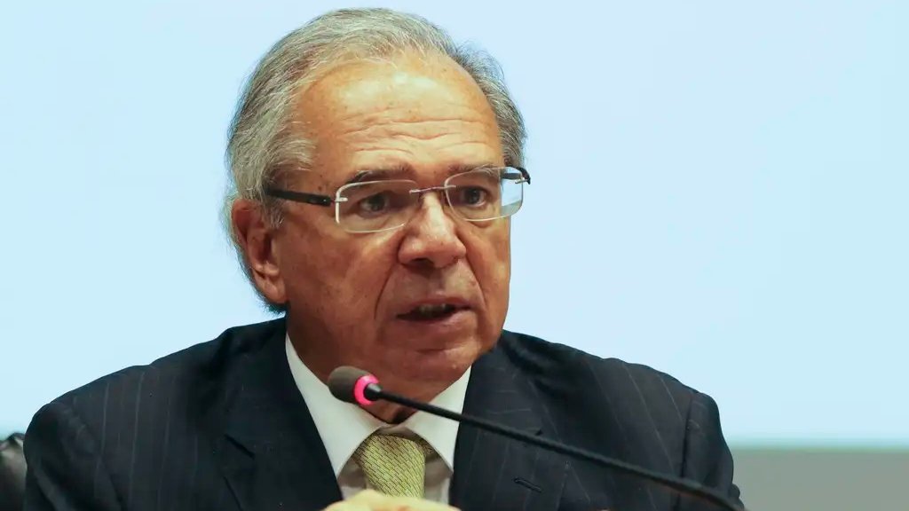 Uma frase dita no momento certo pode mudar o rumo de uma disputa inteira — e foi exatamente essa sensação que Paulo Guedes tentou provocar ao afirmar que a oposição deve vencer a eleição de outubro por causa do baixo crescimento do país. Mas por que uma declaração assim chama tanta atenção? Porque ela não fala apenas de economia. Ela tenta ligar diretamente o humor do eleitor ao desempenho do Brasil, como se uma coisa inevitavelmente empurrasse a outra. E quando alguém que já comandou a área econômica faz esse tipo de previsão, a pergunta surge quase sozinha: ele está apenas opinando ou tentando antecipar um movimento que já enxerga nas ruas? A resposta passa pelo argumento central que ele apresentou. Segundo Guedes, o crescimento fraco da economia brasileira não é um acidente, mas consequência da política fiscal do atual governo. Na visão dele, quando o governo aumenta gastos, emite mais moeda, pressiona a inflação, eleva os juros e, no fim da cadeia, reduz o crescimento. Parece uma explicação técnica, mas o efeito político que ele descreve é bem mais direto: se a economia perde força, o eleitor tende a procurar outro caminho. Só que isso levanta uma dúvida importante: por que essa fala ganhou tanto peso agora? Porque ela marcou a primeira aparição pública de Guedes depois de um período afastado. E esse retorno não veio com um comentário lateral ou uma análise neutra. Veio com uma previsão eleitoral clara, feita diante de uma plateia no Fórum da Liberdade, em Porto Alegre. E é nesse ponto que muita gente se surpreende: ele não falou apenas sobre números, falou sobre consequência política. Mas há um detalhe que quase ninguém percebe de imediato. Ao criticar o presente, Guedes também tentou defender o passado. Ele afirmou que deixou o cargo com previsão de inflação de 3,2% para o ano seguinte e com expectativa de superávit em 5 mil municípios, no governo federal e nas estatais. Ou seja, sua fala não foi só um ataque ao modelo atual, mas também uma tentativa de reforçar a ideia de que sua gestão teria entregue uma base mais sólida do que a narrativa adversária costuma admitir. E por que isso importa tanto? Porque essa versão entra em choque com o discurso repetido por Lula, de que recebeu um governo altamente endividado e precisou aprovar uma PEC para ampliar espaço de gastos antes mesmo de assumir. Foi essa medida, a chamada PEC fura-teto, que permitiu ao novo governo gastar R$ 168,9 bilhões além do limite então vigente. O que acontece depois muda tudo, porque o debate deixa de ser apenas sobre quem tem razão no passado e passa a ser sobre quem conseguirá convencer o eleitor no presente. Só que Guedes não parou no diagnóstico interno. Ele puxou uma comparação internacional. Citou o Chile e disse que o movimento político brasileiro pode repetir o que ocorreu lá, onde o último governo de esquerda foi derrotado na eleição presidencial do ano passado. Segundo ele, Gabriel Boric teve 30% no primeiro turno e 30% no segundo, e “aqui vai acontecer igualzinho”. A comparação é forte, mas também abre outra pergunta: ele estava descrevendo uma tendência real ou tentando ajudar a construí-la? Essa dúvida cresce quando se observa o restante do discurso. Guedes falou de uma aproximação entre liberais na economia e conservadores nos costumes, algo que classificou como o “espírito do tempo”. A frase parece resumir mais do que uma análise: parece apontar para o tipo de aliança que ele vê ganhando espaço em vários países. E, mesmo sem declarar apoio a nenhum nome, ele manteve diálogo com possíveis presidenciáveis presentes no evento, como Romeu Zema, Ronaldo Caiado e Aldo Rebelo. Então ele já escolheu um lado? Publicamente, não. Guedes disse que está focado na iniciativa privada e evitou anunciar apoio a qualquer candidatura. Mas a força da fala não está apenas no que ele confirmou. Está no que deixou no ar. Ao dizer que o baixo crescimento deve empurrar o eleitor “para o outro lado”, ele não entregou só uma previsão. Entregou uma leitura política que tenta transformar desaceleração econômica em combustível eleitoral. E é justamente aí que está o ponto principal: Paulo Guedes usou sua volta ao debate público para afirmar que, se a economia continuar perdendo ritmo, a oposição chegará fortalecida à eleição de outubro. Não como um palpite isolado, mas como consequência direta da política fiscal do governo Lula. A declaração parece simples, mas deixa uma pergunta aberta que ainda deve pesar muito até lá: o eleitor vai punir a economia fraca — ou vai comprar a disputa de narrativas sobre quem realmente a provocou?