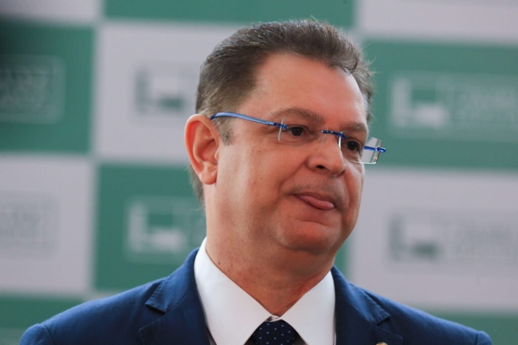 Quando uma demissão acontece no auge da pressão, a pergunta nunca é só quem saiu, mas por que saiu exatamente agora. Foi isso que acendeu o debate nesta segunda-feira. A troca no comando de um dos órgãos mais sensíveis do país não foi lida apenas como uma mudança administrativa. Para um líder da oposição na Câmara, o gesto teve outro peso, outro timing e, principalmente, outra intenção. Mas o que ele quis dizer com isso? Segundo Sóstenes Cavalcante, líder do PL na Câmara dos Deputados, a saída do então presidente do INSS foi um “sacrifício” para “tentar conter o dano”. A fala não veio isolada, nem em tom burocrático. Ela foi publicada nas redes sociais com uma acusação política direta: a de que, depois do que foi exposto, o governo correu para agir. Só que exposto por quem, e sobre o quê? A referência feita por Sóstenes foi à CPMI do INSS, comissão do Congresso que investigou o esquema de descontos não autorizados em aposentadorias e pensões. E é aqui que muita gente começa a prestar mais atenção, porque a crítica não se limita à troca de nomes. Ela sugere que a demissão teria relação com a pressão gerada pelas revelações em torno desse caso. Mas há um ponto que quase passa despercebido: a comissão terminou sem aprovar um relatório final. Então por que o assunto continua tão vivo? Porque, mesmo sem relatório aprovado, os fatos investigados seguiram produzindo efeito político. Foi nesse ambiente que o parlamentar afirmou que “coincidência não é” e levantou uma dúvida que ele próprio tratou como central: o que motivou de verdade essa demissão? A pergunta ganhou força porque a mudança aconteceu depois de semanas de desgaste em torno do tema. E quando uma troca ocorre nesse cenário, a leitura política quase sempre vai além da versão oficial. Mas qual foi essa versão? O governo Lula demitiu Gilberto Waller e nomeou para o lugar dele Ana Cristina Viana Silveira, secretária-executiva adjunta do Ministério da Previdência Social. Em nota, o ministério informou que ela assume com a missão de acelerar a análise de benefícios e simplificar processos internos. Também destacou que a escolha de uma servidora de carreira, com visão sistêmica do fluxo previdenciário, marca um novo momento para o instituto. Parece uma justificativa técnica. Mas por que, então, a reação foi tão política? Porque o contexto pesa. Gilberto Waller havia sido nomeado em 30 de abril de 2025, justamente em meio ao escândalo de desvios de recursos de aposentadorias e pensões, substituindo Alessandro Stefanutto. Ou seja, sua chegada já estava ligada a uma crise. E sua saída, agora, inevitavelmente também foi lida sob a luz dessa mesma crise. O que acontece depois disso muda a interpretação de tudo. Ao comentar a demissão, Sóstenes afirmou que isso “não é solução”, mas “movimento de contenção”. A frase tenta fixar uma ideia: a de que o governo não resolveu o problema, apenas reagiu ao desgaste. E há outro detalhe que ele acrescenta para manter a pressão no ar. Segundo o deputado, quando “a verdade começa a aparecer, alguém sempre é sacrificado”. Mas sacrificado para proteger o quê? Foi aí que ele lançou a dúvida mais sensível de sua manifestação: “Será medo do que vem aí na delação?”. A pergunta não traz resposta no próprio texto, mas funciona como novo combustível político. E é justamente nesse ponto que a narrativa muda de patamar, porque a discussão deixa de ser apenas sobre gestão e passa a tocar em possível temor sobre desdobramentos futuros. Sem afirmar fatos além do que foi dito, a fala do líder do PL tenta empurrar o debate para o que ainda pode surgir. Ao mesmo tempo, ele também acusou deputados e senadores do PT e da esquerda de tentarem blindar o caso na CPMI. Disse ainda que, apesar disso, “a verdade encontra caminho”. Essa construção ajuda a explicar por que a demissão foi tratada por ele como sinal, e não como simples troca de comando. Mas será que essa leitura vai prevalecer? Por enquanto, o fato concreto é este: o governo trocou o presidente do INSS, anunciou uma nova dirigente e apresentou a mudança como parte de um esforço para reduzir filas e melhorar o atendimento aos segurados. Já a oposição enxerga a mesma decisão como resposta à pressão política gerada pela investigação sobre descontos indevidos. E é aqui que a maioria se surpreende: o centro da discussão já não é apenas quem entrou ou quem saiu, mas o que essa troca realmente significa. No fim, a frase que mais ecoa não é a da nomeação, mas a da suspeita. Para Sóstenes, Gilberto Waller foi “sacrificado” para conter danos. Para o governo, a mudança inaugura um novo momento no INSS. Entre uma versão e outra, fica a pergunta que ainda empurra a história adiante: a demissão foi só administrativa ou é o primeiro sinal de algo maior que ainda está por vir?