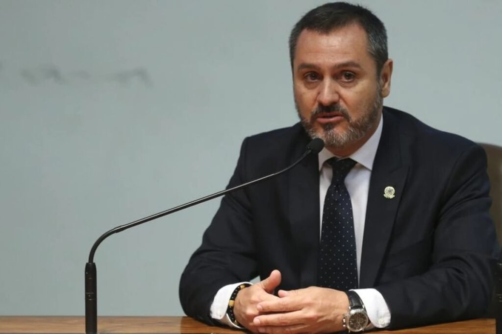 Não foi apenas uma prisão, e é justamente isso que torna esse caso tão mais delicado do que parecia à primeira vista. Se a detenção já chamava atenção por si só, o que realmente mudou a leitura do episódio? A resposta veio de quem ocupa um dos postos mais sensíveis da segurança pública brasileira: houve coordenação com a Polícia Federal. E quando uma prisão fora do país acontece com esse tipo de confirmação, a pergunta deixa de ser apenas “quem foi preso?” e passa a ser “o que estava sendo articulado nos bastidores?”. Mas essa coordenação significa que tudo estava ligado diretamente a um pedido formal de extradição? É aí que a história começa a ganhar uma camada mais complexa. A confirmação feita por Andrei Rodrigues aponta que a prisão foi coordenada com a corporação brasileira, mas o motivo imediato da detenção foi migratório. Isso muda o foco, porque mostra que a captura ocorreu por ação do serviço de imigração dos Estados Unidos, o ICE, e não como simples execução automática de um pedido político ou diplomático. Então por que isso gerou tanta repercussão? Porque havia uma versão circulando entre aliados de que a prisão não teria relação com o pedido de extradição feito pelo governo brasileiro. E é nesse ponto que muita gente se surpreende: a fala do diretor-geral da PF não confirma essa leitura simplificada. Ao dizer que houve coordenação, ele insere a Polícia Federal no centro do episódio e desmonta a ideia de que tudo teria ocorrido de forma isolada, sem interlocução com o Brasil. Mas quem estava no centro dessa operação? Alexandre Ramagem, ex-deputado, foi detido nesta segunda-feira, 13 de abril, em Orlando, na Flórida, por agentes do ICE. Depois disso, foi levado para um centro de detenção por questões migratórias. Só que essa informação, por si só, ainda não explica por que o caso ganhou dimensão tão grande. O que havia antes dessa prisão? Havia uma fuga, uma condenação e um rastro que já vinha sendo acompanhado. Ramagem está nos Estados Unidos desde setembro de 2025, depois de deixar o Brasil no mesmo dia em que o ministro Alexandre de Moraes votou para condená-lo. A decisão levou à decretação de sua prisão. O detalhe que quase passa despercebido é que a saída do país não ocorreu por uma rota comum de exposição máxima. Segundo investigadores da PF, ele deixou o Brasil pela fronteira com a Guiana, em Bonfim, em Roraima, seguindo de carro até cruzar a divisa, separada apenas por um rio. E o que aconteceu depois muda toda a percepção do caso. Já na Guiana, ele embarcou para Miami, com registro de chegada em 11 de setembro. Entrou sozinho nos Estados Unidos, embora depois tenha passado a viver no país com a esposa e os filhos. Se ele já estava fora do Brasil havia meses, por que a prisão só aconteceu agora? A resposta passa por outro ponto decisivo: a situação migratória. Ramagem perdeu o passaporte diplomático após ter o mandato cassado pela Câmara dos Deputados, em dezembro de 2025. Paralelamente, o Ministério da Justiça formalizou em 30 de dezembro de 2025 o pedido de extradição à Embaixada do Brasil em Washington, que encaminhou a documentação ao Departamento de Estado dos EUA. Isso ajuda a entender por que a prisão por questões migratórias não pode ser lida como um fato solto. Mas há um detalhe que quase ninguém percebe: o caso reúne, ao mesmo tempo, uma condenação no Brasil, uma fuga internacional, um pedido formal de extradição e uma detenção executada por autoridades migratórias americanas com coordenação da PF. Quando essas peças se encaixam, a narrativa muda de tom. Já não se trata apenas de onde ele estava, mas de como foi localizado, monitorado e alcançado. E por que a declaração de Andrei Rodrigues pesa tanto? Porque ela dá caráter oficial ao elo entre a ação nos Estados Unidos e a atuação brasileira. Isso contraria a avaliação divulgada por Paulo Figueiredo, cuja empresa é responsável pelo pedido de asilo de Ramagem nos EUA. Após a prisão, ele avisou aliados que a detenção não teria relação com o pedido de extradição do governo Lula. Só que, diante da confirmação de coordenação com a PF, essa versão perde força. No fim, o ponto principal não é apenas que Alexandre Ramagem foi preso em Orlando. O que realmente importa é que a prisão ocorreu dentro de uma operação coordenada com a Polícia Federal brasileira, em um caso que mistura fuga, condenação, fronteira, extradição e questões migratórias. E quando uma captura acontece assim, a dúvida que fica já não é sobre o que houve ontem, mas sobre o que essa articulação ainda pode revelar nos próximos passos.