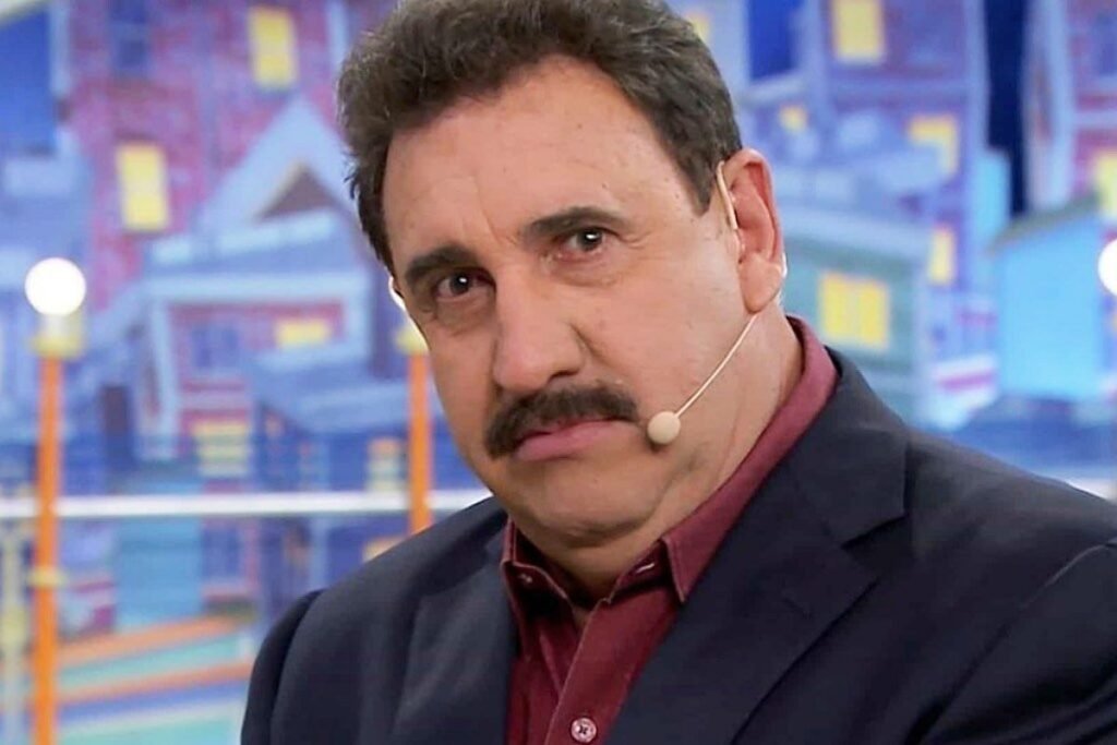 Bastou uma imagem para transformar um rosto conhecido há décadas em motivo de espanto, dúvida e debate. Mas o que chamou tanta atenção? O apresentador **Carlos Massa**, o **Ratinho**, apareceu sem o seu tradicional **bigode**, marca registrada que acompanha sua imagem pública há anos. A surpresa tomou conta do público nesta terça-feira, **7 de abril**, e a reação foi imediata. Só que ele realmente raspou o bigode? Não. O visual diferente surgiu com ajuda de **IA**, a **Inteligência Artificial**, que permitiu a fãs imaginar como ficaria o apresentador do **Programa do Ratinho** sem o famoso bigode preto. E por que isso repercutiu tanto? Porque a mudança mexe justamente com um dos traços mais reconhecíveis de sua aparência. Como ficou o resultado? As imagens mostram o artista do **SBT**, o **Sistema Brasileiro de Televisão**, com o rosto limpo, sem o buço que sempre fez parte de sua identidade visual. Para muitos, a aparência ficou **estranha** e bastante diferente daquilo que o público está acostumado a ver. Para outros, mesmo sem o bigode, o **carisma** do apresentador continuou evidente. Mas essa reação foi unânime? Não. A repercussão dividiu opiniões nas redes sociais. E o que as pessoas disseram? Houve quem comparasse o novo visual a figuras bastante conhecidas. O ex-**BBB** **Rafinha** afirmou que Ratinho ficou com a cara de **Fred Flintstones**, personagem clássico do desenho de **Hanna-Barbera**. Já outro comentário trouxe uma crítica direta e disse que era uma pena que a IA não pudesse deixá-lo sem preconceitos e comportamentos incoerentes. As comparações pararam por aí? Também não. Muitos internautas disseram que ele ficou parecido com **Marrone**, da dupla **Bruno e Marrone**. Outros afirmaram que a semelhança maior foi com o próprio filho, **Ratinho Júnior**. E ainda houve quem observasse outro detalhe no rosto alterado digitalmente, comentando que o **nariz** parecia ainda maior. Diante de tanta curiosidade, surge outra pergunta: Ratinho já falou sobre tirar o bigode de verdade? Sim, e de forma bastante clara. Em entrevistas, o apresentador já revelou que **nunca raspará** o que chama de **“picote”**. Essa decisão não é recente nem casual. Ela está ligada à forma como ele enxerga o próprio rosto e ao papel que o bigode exerce em sua aparência. Mas houve alguma proposta concreta para que ele mudasse o visual? Houve, e não foi pequena. Segundo o próprio Ratinho, uma **marca de lâmina de barbear** chegou a oferecer **um milhão** para que ele raspasse a barba. Ele recusou. E por que não aceitou? De acordo com o apresentador, sem o bigode sua boca fica parecendo **“o orifício de um pato”**, porque seu **queixo é projetado para frente**. Então o bigode tem apenas valor estético? Pelo que ele mesmo já declarou, vai além disso. Ratinho afirma que o bigode **compensa imperfeições** e **equilibra seu visual**. Isso ajuda a entender por que a imagem sem esse traço causou tanto impacto. Não se tratava apenas de uma mudança qualquer, mas da retirada de um detalhe que, para ele e para o público, faz parte da composição do seu rosto. E o que ficou dessa repercussão toda? Ficou a confirmação de que o **bigode icônico** de **Carlos Massa** continua sendo inseparável de sua imagem. A foto que assustou o público não mostrava uma transformação real, mas uma simulação feita com **Inteligência Artificial**. Ainda assim, bastou para provocar espanto, comparações, críticas, elogios e relembrar uma posição que o apresentador já deixou definitiva: ele já disse que **nunca vai raspar o “picote”**, mesmo depois de receber **um milhão** para isso, porque considera que o bigode corrige o visual e evita que sua boca, com o **queixo projetado para frente**, fique parecendo **“o orifício de um pato”**.