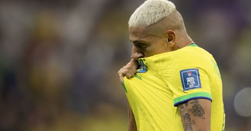 Ele parecia ter chegado ao topo, mas foi justamente depois disso que tudo desabou. Como alguém que disputa uma Copa do Mundo pode sair dela mergulhado no pior momento da própria vida? A resposta não veio em campo, nem em um lance decisivo, mas no silêncio que costuma aparecer quando o barulho acaba. Após a eliminação do Brasil em 2022, o atacante Richarlison contou que entrou em depressão. E o mais inquietante é que aquilo não foi um impacto isolado, passageiro, de quem apenas sofreu uma derrota. Então o que havia por trás dessa queda? Segundo o próprio jogador, não era só a frustração pela Copa. Ele descreveu uma sequência de problemas que se acumularam fora de campo e transformaram aquele período em algo muito mais pesado. Questões pessoais, conflitos com o ex-agente, problemas familiares e lesões passaram a agir ao mesmo tempo. E é justamente aí que muita gente se surpreende: o que parecia ser apenas uma reação esportiva era, na verdade, o centro de uma avalanche emocional. Mas por quanto tempo isso durou? Não foram dias, nem semanas. Richarlison afirmou que viveu cerca de um ano e meio de dificuldades. Isso muda a dimensão do relato, porque deixa de ser um momento ruim e passa a ser uma fase longa, desgastante, difícil de sustentar. E quando um problema se estende por tanto tempo, a pergunta inevitável aparece: até onde isso pode levar alguém? A resposta é a parte mais dura do relato. Em entrevista à revista France Football, o atacante disse que, em um dos momentos mais críticos, enquanto dirigia, pensou em se chocar contra um muro. Depois, ao olhar para trás, afirmou que hoje vê que aquilo não fazia sentido. Mas há um detalhe que quase ninguém percebe quando lê uma frase assim: ela não fala apenas de desespero, fala do ponto em que a mente pode chegar quando tudo parece desmoronar ao mesmo tempo. E o que acontece depois de um pensamento assim? É aqui que o rumo da história começa a mudar. Richarlison destacou que o acompanhamento psicológico foi determinante para sua recuperação. O trabalho com profissionais e o apoio de pessoas próximas, segundo ele, ajudaram a mudar o cenário. Isso não apaga o que aconteceu, mas revela algo essencial: a saída não veio de um passe de mágica, e sim de cuidado, suporte e tratamento. Só que essa não é a única camada da história. Se esse período recente já parece pesado, de onde vem a resistência para continuar? A resposta passa pela infância do jogador, muito antes da fama, dos estádios lotados e da pressão internacional. Richarlison relembrou a vida em Nova Venécia, no Espírito Santo, e descreveu um ambiente marcado por violência e proximidade com o crime. Ele disse que recusou convites para atividades ilegais e relatou episódios de risco. Em um deles, uma bala passou perto de sua cabeça. Ele teve medo de morrer. Por que isso importa agora? Porque ajuda a entender que a trajetória dele nunca foi linear. O futebol, para Richarlison, não surgiu apenas como carreira, mas como saída. Projetos sociais e o esporte foram caminhos para escapar daquele contexto. O que acontece depois muda tudo, porque essa lembrança reposiciona o presente: o jogador que hoje fala sobre depressão também é alguém que já precisou sobreviver a outros tipos de ameaça. E como essa história segue daqui para frente? Atualmente no Tottenham Hotspur, o atacante projeta a retomada da carreira e mira a disputa da Copa do Mundo de 2026. Ele também citou referências como Neymar, Ronaldo e Pelé na própria trajetória. Mas o ponto principal não está apenas no próximo torneio, nem no retorno técnico, e sim no que seu relato expõe com força rara: mesmo no auge da visibilidade, alguém pode estar enfrentando uma batalha invisível. No fim, a frase “todas as desgraças possíveis caíram sobre mim” não resume só um período ruim. Ela revela o peso de uma sequência de dores que quase levou tudo junto. E talvez o mais importante esteja justamente no que ainda continua em aberto: a recuperação começou, os planos seguem vivos, mas a história que ele contou vai muito além do futebol — e talvez seja por isso que ela ainda ecoe tanto depois da última linha.