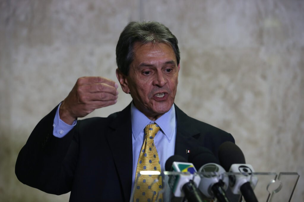 Uma decisão da Justiça recoloca no centro de um episódio violento uma pergunta inevitável: quanto custa, na esfera civil, o dano sofrido por uma agente da **Polícia Federal** durante o cumprimento de um mandado de prisão? A resposta não veio de imediato, mas agora tem valor definido e nome envolvido. **Roberto Jefferson** foi condenado a pagar **R$ 200 mil** em indenização por **danos morais** à agente **Karina de Oliveira**. Mas de onde nasce essa condenação? Ela decorre do episódio ocorrido em **outubro de 2022**, quando policiais foram cumprir um mandado de prisão contra o ex-deputado federal. Na ocasião, a agente sofreu ferimentos na **cabeça**, no **cotovelo** e no **joelho** após **disparos de fuzil** e o lançamento de **granadas**. Foi esse contexto que levou a ação à Justiça e resultou na decisão proferida em primeira instância. E quando essa decisão foi tomada? A sentença é da última **quarta-feira (1º)** e foi assinada pelo juiz **Eduardo Buzzinari Ribeiro de Sá**, do **Tribunal de Justiça do Estado do Rio de Janeiro**, o **TJRJ**. Ainda cabe destacar que se trata de uma decisão de **primeira instância**, o que significa que o caso ainda pode ter novos desdobramentos. A condenação reconheceu todos os pedidos feitos pela agente? Não. O magistrado reconheceu a existência de **dano moral**, mas negou o pedido de **dano estético** relacionado a eventuais sequelas. Por quê? Segundo a decisão, a agente apresentou aos autos apenas **fotografias** e não solicitou a realização de **perícia**, o que foi considerado insuficiente para comprovar esse tipo específico de dano. Então, o que sustentou o reconhecimento do dano moral? O juiz levou em conta o período de **45 dias de recuperação**, comprovado por **laudo médico**. Esse tempo foi considerado relevante para caracterizar o abalo sofrido pela policial. Ou seja, mesmo sem o reconhecimento de dano estético, houve base documental para a reparação por dano moral. A defesa de Roberto Jefferson apresentou contestação? Sim. Ao responder à ação, a defesa argumentou que policiais devem possuir **equilíbrio emocional** e **resiliência necessária** para atuar em situações de **alto risco** e **pressão constante**. Também apontou que a agente recebeu **alta no mesmo dia**. A discussão, então, passou a girar em torno de uma questão sensível: a natureza da atividade policial afastaria o direito à reparação civil? A resposta do juiz foi direta. Não. Na decisão, o magistrado afirmou que esse argumento não se sustenta. Embora reconheça que a exposição ao risco faz parte da atividade policial, ele entendeu que isso não elimina o direito de buscar **reparação civil** por danos causados deliberadamente por terceiros durante o exercício da profissão. E o quadro clínico da agente foi tratado como algo menor por causa da alta rápida? Também não. Apesar da liberação médica no mesmo dia, Karina de Oliveira deu entrada no **Hospital Nossa Senhora da Conceição** com classificação de **“muito urgente”**. No dia seguinte, passou por uma **cirurgia** para retirada de um **estilhaço no quadril**, após enfrentar uma **inflamação**. Esse histórico reforçou a gravidade do que ocorreu, independentemente da alta inicial. Qual foi exatamente o entendimento do magistrado sobre esse ponto? Ele registrou: **“O argumento de que policiais devem possuir equilíbrio emocional e resiliência necessária para atuar em situações de alto risco e pressão constante igualmente não se sustenta. Embora a exposição a situações de risco seja inerente à natureza do trabalho policial, tal circunstância não elide o direito de se pretender a reparação civil por eventuais danos deliberadamente causados por terceiros contra si no exercício da profissão”**. E houve manifestação da defesa após a decisão? Até o momento citado, não. A **Gazeta do Povo** informou que entrou em contato com a defesa de **Roberto Jefferson** e **aguarda retorno**. No fim, o que ficou definido até aqui? Ficou estabelecido, em **primeira instância**, que **Roberto Jefferson foi condenado a pagar R$ 200 mil em indenização por danos morais à agente da Polícia Federal Karina de Oliveira**, em razão dos ferimentos sofridos durante o cumprimento do mandado de prisão em **outubro de 2022**.