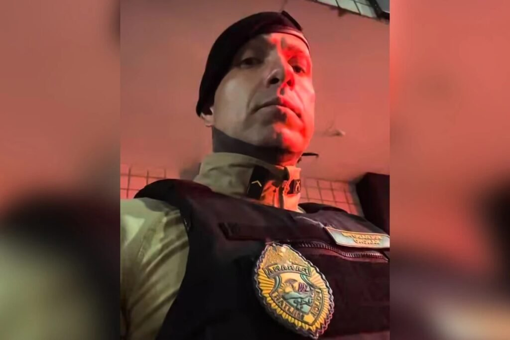 A prisão de um **PM influenciador** com centenas de milhares de seguidores abriu uma investigação que vai muito além da imagem exibida nas redes sociais. Quem é esse policial? Trata-se de **Junior Sancho Cambuhy**, conhecido como **“Sancho Loko”**, preso durante uma operação do **Grupo de Atuação Especial de Combate ao Crime Organizado (Gaeco)**, do **Ministério Público do Paraná**. Mas por que a operação foi deflagrada? Porque, além dele, outros **dois policiais militares** são investigados pelo possível cometimento, de forma reiterada, dos crimes de **tortura**, **fraude processual**, **lesão corporal** e **falsidade ideológica**. Quando isso aconteceu? A ação ocorreu na **terça-feira, 7 de abril**, em **Curitiba**. E como essa operação foi executada? Foram cumpridos **quatro mandados de busca e apreensão**, expedidos pela **Vara de Auditoria da Justiça Militar**. Onde esses mandados foram cumpridos? **Três** deles nas residências dos investigados e **um** no batalhão onde eles estão lotados, na capital paranaense. O que foi encontrado durante as buscas? As equipes do **Gaeco** apreenderam **telefones celulares** e outros itens de **armazenamento eletrônico**, materiais que poderão auxiliar na apuração dos fatos. Houve outras apreensões? Sim. Nas residências de **dois dos investigados**, foram encontradas **munições irregulares** e **dinheiro em espécie**. E o que apareceu dentro da unidade da Polícia Militar? Em **armários sem identificação**, foram localizados **simulacros de arma de fogo**, **munições irregulares**, além de **maconha**, **crack** e **cocaína**. Foi nesse contexto que **Sancho Loko acabou preso**. Qual é a dimensão pública desse nome? **Sancho Loko** atua como **influenciador digital** e soma mais de **260 mil seguidores no Instagram**. Isso ajuda a explicar por que o caso ganhou repercussão imediata, mas não altera o foco da investigação, que está concentrado nos fatos apurados pelas autoridades. Quem participou da operação além do Gaeco? A ação contou com o apoio da **Corregedoria-Geral da Polícia Militar**, reforçando o caráter institucional da apuração. E o que disse a defesa do policial? Por meio das redes sociais, o advogado **Claudio Dalledone**, que também é influenciador digital, publicou um vídeo se pronunciando oficialmente após a prisão do cliente. Qual foi a versão apresentada pela defesa? Dalledone afirmou que **Sancho Loko é inocente** e declarou que os equipamentos encontrados com ele, que ocasionaram a prisão, seriam **materiais usados nas aulas de tiro**, atividade em que o policial atua como **instrutor**. E qual foi a posição oficial da corporação? Em nota, a **Polícia Militar do Paraná (PMPR)** informou que será instaurado o **procedimento administrativo cabível** para apuração dos fatos. O que permanece sob investigação? As suspeitas envolvendo os possíveis crimes de **tortura**, **fraude processual**, **lesão corporal** e **falsidade ideológica**, além da análise do material apreendido durante a operação. Quem foi preso, afinal, e em que circunstância? Foi preso o policial militar e influenciador **Junior Sancho Cambuhy**, conhecido como **“Sancho Loko”**, durante operação do **Gaeco**, em **Curitiba**, no dia **7 de abril**, no âmbito de uma investigação que também envolve outros **dois policiais militares**.