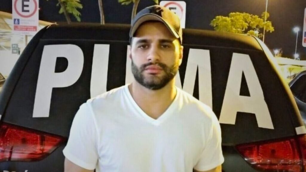 Como alguém pode ser **enterrado antes de morrer** sem que isso acenda um alerta imediato em todo mundo? Foi exatamente essa contradição que chamou atenção em um caso já cercado por dúvidas. Um registro oficial indicava que o sepultamento havia acontecido quase **um mês antes** da data da morte. E, quando uma informação assim aparece em sistema público, a primeira pergunta surge sozinha: trata-se de algo muito mais grave ou de um erro que ganhou proporções maiores por causa de quem estava no centro da história? A resposta inicial aponta para a segunda hipótese. Segundo a administração municipal, a divergência foi resultado de uma **falha humana pontual** no lançamento dos dados. O problema teria sido identificado depois e corrigido de forma imediata. Mas se foi apenas um erro de digitação, por que isso provocou tanta repercussão? Porque o detalhe não estava isolado. O nome envolvido já aparecia em um episódio sensível, com prisão, atendimento hospitalar e morte cercada por questionamentos. E é justamente aí que a maioria se surpreende: quando um registro público apresenta uma inconsistência tão evidente em um caso delicado, a dúvida deixa de ser apenas técnica e passa a parecer parte de algo maior. Então o que exatamente constava no sistema? O registro municipal apontava que o sepultamento teria ocorrido em **8 de fevereiro**. O problema é que a morte foi registrada apenas em **6 de março**, semanas depois. A diferença entre as datas transformou um simples lançamento em uma contradição impossível de ignorar. Mas há um detalhe que quase ninguém percebe de início: o erro não surgiu em um caso comum, e isso muda completamente a forma como a informação é recebida. Quem era a pessoa citada nesse registro? Tratava-se de **Luiz Phillipi Machado de Moraes Mourão**, conhecido como **“Sicário”**. A morte dele ocorreu em **Belo Horizonte**, depois de ele ter sido preso pela **Polícia Federal** e encaminhado para atendimento médico. Só que, antes mesmo de se discutir a inconsistência do enterro, outra pergunta já dominava o caso: o que aconteceu entre a prisão e a confirmação da morte? Segundo as informações divulgadas, ele foi preso e, no mesmo dia, tentou tirar a própria vida na carceragem da Polícia Federal. Depois disso, foi levado ao **Hospital João XXIII**, na capital mineira. A morte foi confirmada posteriormente, no dia 6, após um quadro de **falta de oxigenação no cérebro**. Mas se essa sequência está descrita, por que ainda restaram dúvidas? Porque a própria **certidão de óbito** não especificou a causa da morte. O documento informou apenas que o caso estava **“aguardando exames”**. E o que acontece depois muda tudo: quando a causa não está fechada no momento do registro, especialistas apontam que isso pode ocorrer em situações em que o enterro precisa ser realizado antes da conclusão dos laudos periciais. Isso ajuda a entender a ausência de definição médica imediata, mas não explica a data impossível no sistema. Então onde entra a explicação oficial? A **Prefeitura de Belo Horizonte** afirmou que a divergência foi causada por erro de digitação no sistema. Em nota, informou que o equívoco foi identificado posteriormente e corrigido de forma imediata. Também declarou que o sistema já estava atualizado, sem inconsistências relacionadas ao caso. Além disso, a **Fundação de Parques Municipais e Zoobotânica** classificou o episódio como uma ocorrência isolada, sem registro de falhas semelhantes no período. E onde o sepultamento foi registrado? De acordo com o sistema municipal, o enterro ocorreu no **Cemitério do Bonfim**, um dos mais tradicionais de Belo Horizonte. Esse dado permaneceu ligado ao caso, mas o ponto que realmente incendiou a atenção pública foi a inversão das datas. Afinal, quando um sistema oficial sugere que alguém foi sepultado antes de morrer, a impressão imediata é de que existe algo oculto. Só que, até aqui, a versão oficial é outra: não houve antecipação real do enterro, e sim um **lançamento incorreto**. Mas será que isso encerra a história? Não completamente. O registro foi corrigido, a prefeitura sustentou a tese de **erro de digitação**, e a inconsistência formal foi resolvida. Ainda assim, o caso continua chamando atenção porque a falha apareceu justamente em uma morte já marcada por investigação, lacunas documentais e expectativa por exames. No fim, o ponto principal não é que **“Sicário” foi enterrado antes de morrer**, mas que um erro simples, quando surge no lugar e no momento errados, é suficiente para transformar um dado burocrático em mais uma peça de um caso que ainda desperta perguntas.