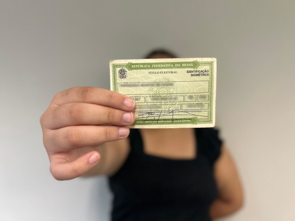 Os números chamam atenção logo de saída: **São Paulo** e **Rio de Janeiro** aparecem com os menores percentuais de adolescentes com **título de eleitor** em todo o país. Mas quão baixa é essa participação? Segundo dados do **TSE** compilados pelo **Unicef**, a diferença fica evidente quando se observa o tamanho dessa faixa etária e quantos, de fato, buscaram o documento. Quem são esses jovens e por que esse recorte importa? Trata-se dos adolescentes de **16 e 17 anos**, grupo para o qual o **voto é facultativo** no Brasil. O país tem cerca de **5,8 milhões** de adolescentes nessa faixa etária. Ainda assim, até fevereiro, apenas cerca de **1,8 milhão** de jovens de **15, 16 e 17 anos** haviam tirado o título. O resultado prático é direto: apenas **dois em cada dez jovens** estavam aptos a votar. Onde essa baixa adesão aparece com mais força? No **Sudeste**, e de forma mais intensa justamente nos dois maiores estados da região. Em **São Paulo**, há cerca de **1,19 milhão** de adolescentes de 16 e 17 anos, mas pouco menos de **139 mil** haviam se registrado como eleitores. No **Rio de Janeiro**, são mais de **419 mil** jovens nessa faixa etária, com cerca de **47,5 mil** títulos emitidos. Se SP e RJ estão na ponta de baixo, onde os adolescentes têm participado mais? Os percentuais mais altos estão em estados do **Norte** e do **Nordeste**. O levantamento mostra que, enquanto o Sudeste concentra a adesão mais baixa, essas duas regiões apresentam participação significativamente maior entre adolescentes. Esse cenário é novo ou varia com o tempo? Os dados indicam que o interesse dos adolescentes pelo voto muda de uma eleição para outra. Em **2022**, mais de **2 milhões** de jovens haviam tirado o título, o equivalente a **34%** do total apto. Já em **2018**, esse percentual era de aproximadamente **21%**. Agora, para **2026**, o índice atual de **20,3%** coloca o país em um patamar semelhante ao de oito anos atrás e abaixo do registrado na última eleição presidencial. Diante dessa adesão reduzida, houve alguma reação institucional? Sim. O **Unicef**, em parceria com o **TSE**, lançou uma campanha nacional para incentivar adolescentes a exercer o direito ao voto. A iniciativa busca mobilizar jovens para além da presença nas redes sociais e reforçar a participação por meio do processo eleitoral. Como essa mobilização está sendo feita? A campanha reúne ações nas **redes sociais**, atividades em **escolas** e uma espécie de **gincana digital** voltada aos **Núcleos de Cidadania do Adolescente**, os **NUCAs**, presentes em mais de **2,3 mil municípios** participantes do **Selo Unicef**. A proposta inclui premiar grupos que consigam aumentar proporcionalmente o número de jovens com título de eleitor e estimular a produção de conteúdos criativos sobre o tema. E qual é a justificativa apresentada para esse esforço? A especialista em Desenvolvimento e Participação de Adolescentes no Unicef no Brasil, **Gabriela Mora**, resumiu a proposta ao afirmar: **“O Unicef se juntou ao TSE para fazer uma provocação para os adolescentes exercerem o seu direito à cidadania e escolherem o seu presente e o seu futuro por meio do voto. Não adianta se indignar só nas redes sociais. O voto é que vai fazer uma incidência direta no que vai acontecer com as políticas públicas das quais essa geração depende para o seu próprio desenvolvimento”**. O que os adolescentes precisam fazer para votar neste ano? É necessário solicitar o **título de eleitor** até **6 de maio**. Esse prazo também vale para quem precisa **transferir o domicílio eleitoral** ou **regularizar o documento**. Quem vai completar **18 anos até 6 de maio** precisa tirar o título para votar na eleição deste ano. Jovens a partir de **15 anos** já podem solicitar o documento, mas só poderão votar se completarem **16 anos até o dia da eleição**. No fim, o retrato fica completo: o Brasil tem milhões de adolescentes em idade de participação facultativa, mas a adesão segue baixa; **São Paulo** e **Rio de Janeiro** registram os menores índices do país; **Norte** e **Nordeste** concentram os percentuais mais altos; e o prazo para emitir, transferir ou regularizar o **título de eleitor** termina em **6 de maio**.