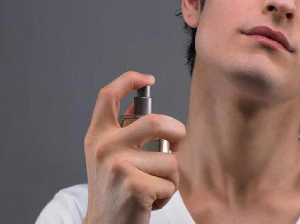 Parece um gesto inofensivo, quase automático, mas passar **perfume no pescoço** pode criar um problema que muita gente só percebe quando a pele já reagiu. Como algo tão comum poderia trazer risco? A dúvida faz sentido, porque o perfume está ligado a cuidado, presença e bem-estar. E justamente por isso quase ninguém para para pensar no lugar onde aplica. O pescoço costuma ser uma escolha óbvia: é uma área quente, ajuda a espalhar a fragrância e mantém o cheiro por mais tempo. Então por que evitar? A resposta não está exatamente no perfume sozinho. Está no que pode acontecer depois. Quando certas fragrâncias entram em contato com a **luz solar**, a pele pode reagir de forma indesejada. E é nesse ponto que muita gente se surpreende: o problema não é apenas “sensibilidade”, mas uma reação já observada pela ciência, conhecida como **reação fototóxica causada por fragrâncias**. Mas isso significa que todo perfume faz mal? Não. E esse é o detalhe que quase ninguém percebe. O risco depende da **composição da fragrância**, da **exposição ao sol** e também do tempo entre a aplicação e o contato com a luz UV. Um estudo indicou que a pele pode ficar mais sensível por até **duas horas após aplicar o perfume**, justamente o período em que a atenção deveria ser maior. E o que isso pode provocar? Em alguns casos, podem surgir **manchas**, **irritações**, processos inflamatórios e até **danos às células da pele**. Parece exagero? Não quando se observa quais ingredientes estão por trás disso. Certos componentes de origem **cítrica** aparecem entre os principais responsáveis por esse efeito. Um exemplo importante é o **óleo de bergamota**, bastante usado em fragrâncias e associado a reações de **fototoxicidade**. Além dele, compostos chamados **furocumarinas** também podem desencadear respostas indesejadas na pele. Mas se o problema está nesses ingredientes, por que o pescoço chama tanta atenção? Porque essa é uma região **delicada**, frequentemente exposta ao sol e que costuma mostrar sinais de envelhecimento mais cedo do que outras áreas. Ou seja, quando perfume e radiação solar se encontram ali, o impacto pode ser mais perceptível. O que acontece depois muda tudo: aquilo que parecia só um hábito de rotina pode virar um gatilho para desconforto e marcas na pele. E existe outro medo que circula bastante: o perfume no pescoço poderia afetar a **tireoide** ou agir como **disruptor endócrino**? Até o momento, não há **evidências científicas conclusivas** que comprovem esse efeito em perfumes regulamentados e de uso comum. Isso quer dizer que está totalmente descartado? Também não. Mas, com base no que já se sabe, a preocupação mais relevante continua sendo outra: a **fotossensibilidade**. Há, porém, um ponto que merece ainda mais atenção. Se perfumes comuns já exigem cuidado, os **falsificados**, sem origem confiável ou sem certificação, aumentam a incerteza. Nesses casos, a composição pode não ser clara, o que amplia os riscos e dificulta prever como a pele vai reagir. E é aqui que surge a pergunta mais prática de todas: então onde aplicar? Especialistas indicam regiões **menos sensíveis**, como os **pulsos**, **atrás das orelhas** e a **parte interna dos cotovelos**. Esses pontos também ajudam a difundir o aroma ao longo do dia, mas com menor chance de irritação. Outra saída é borrifar o perfume na **roupa**, com cuidado em tecidos delicados, que podem manchar. Também dá para aplicar a fragrância em um **pente** e passá-lo levemente no cabelo, evitando o contato direto com a pele. Ainda assim, como saber se um perfume específico pode causar reação? Uma medida simples faz diferença: testar antes em uma **pequena área do corpo**. Isso ajuda a identificar possíveis respostas da pele e evita surpresas desagradáveis. Parece pouco, mas muda bastante a forma de usar fragrâncias com segurança. No fim, o alerta não é para abandonar o perfume nem para tratar o pescoço como uma área proibida. O ponto principal é outro, e ele só fica claro quando todas as peças se encaixam: o maior risco está na combinação entre **fragrância** e **sol**, especialmente quando há ingredientes fotossensíveis na fórmula. O pescoço entra nessa história porque reúne calor, exposição e delicadeza em uma mesma região. E talvez seja justamente por isso que um hábito tão comum mereça ser revisto antes da próxima borrifada.