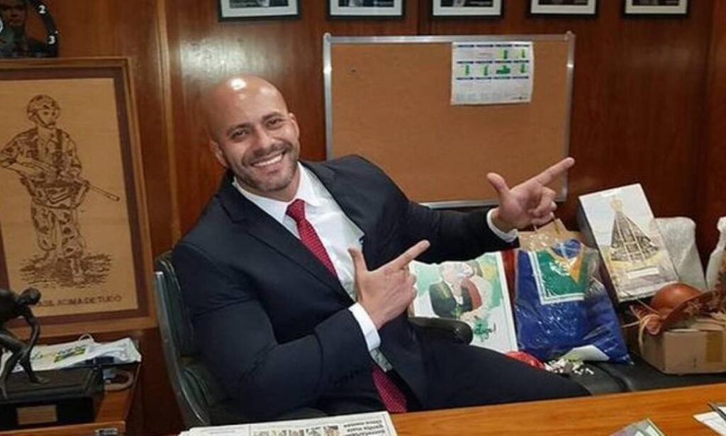 Alexandre de Moraes voltou a mirar em Daniel Silveira por causa de um simples vídeo de apoio político, gravado por terceiro e postado nas redes sociais, e agora pode mandar o ex-deputado de volta para a prisão. A defesa correu ao STF para tentar evitar o pior e argumentou que Silveira nem sequer olha para a câmera, não pediu para gravar, não publicou nada e não usou nenhuma rede social. Mesmo assim, o ministro trata o caso como possível descumprimento de ordem judicial. Por que um vídeo tão simples virou caso de prisão? Porque Moraes considera que qualquer aparição de Silveira em rede social, mesmo gravada por outra pessoa, pode ser violação da proibição imposta como condição do regime aberto. Até onde vai o poder de Moraes? Hoje, na prática, vai até decidir se um ex-deputado pode ou não falar em público sem correr risco de voltar para a cadeia. A esquerda aceitaria isso contra um aliado? Não. Quando o alvo é de esquerda, o discurso é de liberdade de expressão, pluralidade e democracia; quando é da direita, o silêncio é imposto e aplaudido. O que Daniel Silveira fez nesse vídeo? Ele apenas declarou apoio à reeleição do senador Carlos Portinho (PL-RJ) em uma breve interação social, segundo a própria defesa. Desde quando apoiar um senador é crime? Não é crime. O que está em jogo é a interpretação elástica de uma decisão judicial para calar um adversário político específico. Por que só a direita é calada nas redes? Porque o sistema jurídico e midiático trata qualquer fala da direita como ameaça à democracia, enquanto relativiza abusos e discursos radicais quando vêm da esquerda. Isso é proteção da democracia ou controle político? Parece muito mais controle político, com uso do Judiciário para disciplinar quem ousa enfrentar o establishment. O STF virou fiscal de opinião política? Na prática, sim. Quando um ministro decide quem pode falar, o que pode falar e onde pode aparecer, já não é só juiz: é censor. Qual o recado para a base conservadora? O recado é claro: se você é de direita e apoia Bolsonaro ou aliados, qualquer gesto público pode ser usado contra você. Quem ganha com Daniel Silveira calado? Ganha a velha política, ganha a esquerda que posa de vítima, ganha quem tem medo da força eleitoral da direita em 2026. Silveira cumpre pena de oito anos e nove meses por "ameaça ao Estado Democrático de Direito" e "coação no curso do processo". Agora, o mesmo Estado que diz defender a democracia discute se um apoio político em vídeo, gravado por outra pessoa, é motivo para jogar o ex-deputado de volta atrás das grades. É isso mesmo que chamam de Estado Democrático de Direito? A defesa foi direta: foi uma "breve interação social, espontânea e protocolar, registrada unilateralmente por terceiro". Silveira não tinha domínio sobre a produção nem sobre a divulgação do conteúdo. Em qualquer cenário minimamente equilibrado, isso seria visto como exagero jurídico. Mas, quando o alvo é bolsonarista, tudo vira pretexto. Enquanto isso, figuras da esquerda seguem falando o que querem, atacando instituições, defendendo ditaduras amigas e relativizando violência política sem qualquer risco de perder a liberdade. Dois pesos, duas medidas. A tal "ameaça bolsonarista" é usada como desculpa perfeita para justificar qualquer abuso, qualquer censura, qualquer perseguição. Moraes já deixou claro: a proibição de uso de redes sociais é condição do regime aberto. O problema é que, agora, até aparecer no vídeo de outra pessoa pode ser interpretado como uso indireto de rede social. A linha foi cruzada: não é mais sobre plataforma, é sobre voz. Quem pode falar? Quem o STF deixar. O caso de Daniel Silveira é um alerta para todo o campo conservador: se um ex-deputado pode ser ameaçado de prisão por uma fala rápida em apoio a um senador do PL, o que impede que amanhã qualquer cidadão comum seja enquadrado por um simples vídeo, um comentário ou um compartilhamento? O Brasil está vendo, cansado e indignado: quando a Justiça escolhe lado, a democracia perde. E, neste momento, o alvo preferencial tem nome, sobrenome e posição política bem definida: a direita.