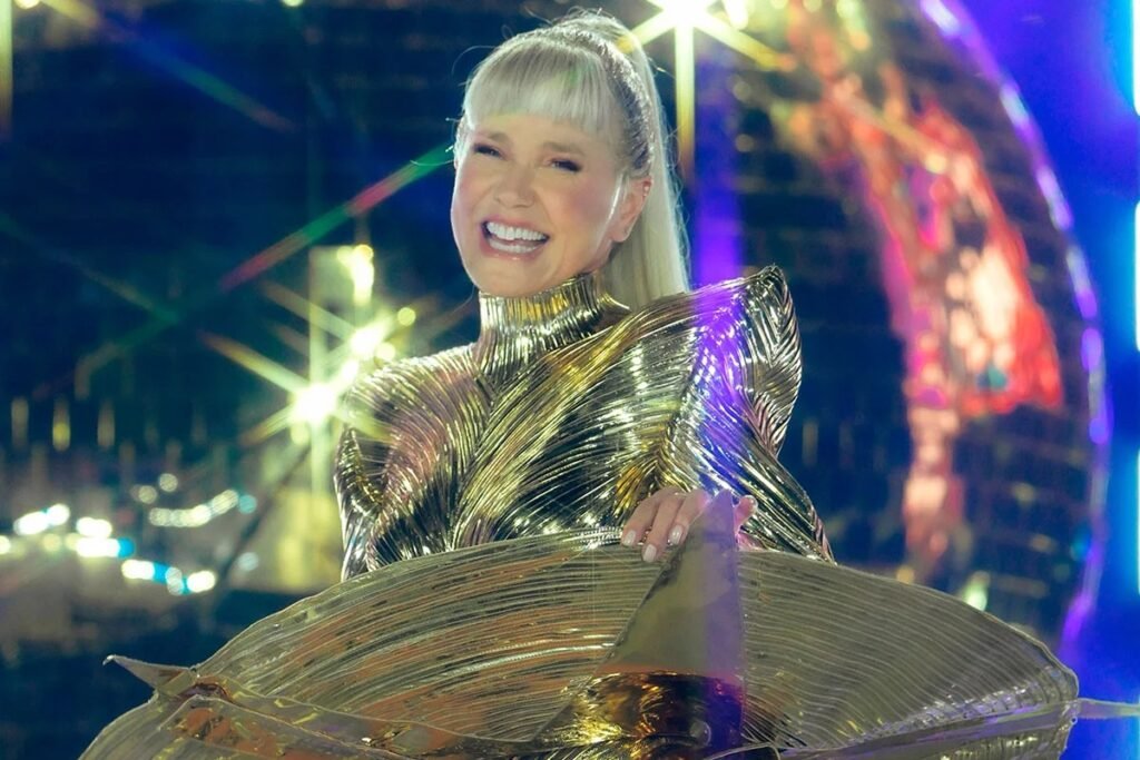 Xuxa foi na TV aberta, em pleno Mais Você, e escancarou: as críticas à sua nova turnê não a derrubaram, pelo contrário, fizeram as vendas dispararem. A apresentadora agradeceu publicamente aos haters e ainda debochou das reclamações sobre suas roupas, rugas e idade. Em outras palavras: quanto mais polêmica, mais ingresso vendido. Ela contou que, depois do primeiro show da turnê “O Último Voo da Nave”, veio uma enxurrada de ataques de quem nem acompanha seu trabalho. E qual foi a reação? “Muito obrigada por vocês terem me criticado, porque depois que vocês fizeram isso, as vendas aumentaram muito”, disse, sem nenhum constrangimento. A mensagem é clara: fale bem ou fale mal, mas fale de mim. Xuxa deixou explícito que o engajamento negativo virou estratégia. Ela mesma admitiu que os comentários, mesmo detonando sua aparência e idade, ajudam a levar a turnê para mais lugares. Ou seja, a cultura do cancelamento virou combustível de marketing. Quem critica, sem perceber, está ajudando a encher os bolsos e os shows. Aos 63 anos, ela ainda fez questão de avisar que vai manter os maiôs, os “chucas” e o figurino colado dos anos 80 e 90. Para quem questiona se “já não passou da idade”, a resposta veio em tom de ironia: vai continuar “mostrando a virilha, ou melhor, o talento”. A provocação é direta, calculada e, pelo visto, lucrativa. Enquanto muita gente comum perde emprego por uma frase errada nas redes, celebridade pode debochar de crítica, transformar tudo em campanha e ainda ser aplaudida em programa matinal. Dois pesos, duas medidas: o público se divide, briga, se engaja, e o caixa da turnê agradece. Xuxa também deixou claro que está falando com o público que cresceu com ela, explorando a nostalgia ao máximo. Figurino futurista, referência a She-Ra, bodies que ela usa há mais de 40 anos. Tudo pensado para mexer com a memória afetiva e, claro, com o bolso de quem ainda compra o pacote completo da “rainha dos baixinhos”. No fim, a mensagem que fica é incômoda: a polêmica virou produto. A crítica virou propaganda. E o debate sobre limites, idade, exposição e respeito vira apenas mais um combustível para vender ingresso. Por que Xuxa agradece tanto críticas? Porque ela mesma admitiu que, depois das críticas, as vendas da turnê aumentaram muito. Críticas negativas aumentaram mesmo as vendas? Segundo a própria Xuxa, sim: após os ataques, o interesse pelo show cresceu e os ingressos dispararam. Engajamento negativo virou estratégia oficial? Pelo que ela disse no programa, sim: qualquer comentário, até de hater, ajuda a impulsionar a turnê. Xuxa realmente debochou da própria idade? Ela ironizou, dizendo que a “tia Xuxa” tem 63 anos, mas vai continuar se apresentando como o público lembra. Ela vai mudar figurino por causa das críticas? Não. Xuxa afirmou que os maiôs, chucas e figurinos clássicos vão continuar nos shows. A polêmica ajuda a vender mais ingressos? Ajuda, e muito. A própria apresentadora disse que a repercussão negativa ampliou o alcance da turnê. O público antigo ainda compra essa nostalgia? Sim, é justamente esse público que ela mira, usando figurinos e estética dos anos 80 e 90. Xuxa está preocupada com haters na internet? Pelo discurso dela, não. Ela agradece os haters porque eles geram mais visibilidade e lucro. A TV apoia essa estratégia de polêmica? Ao dar espaço em programa matinal para esse discurso, a emissora ajuda a amplificar a narrativa. Crítica hoje virou combustível de marketing? No caso de Xuxa, claramente sim: quanto mais falam dela, mais a turnê cresce e fatura.