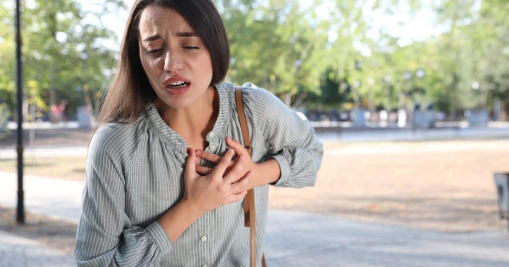 Um estudo com 515 mulheres, publicado na revista Circulation, escancara um dado incômodo: quase 80% delas sentiram sinais de alerta por mais de um mês antes do ataque cardíaco – e quase ninguém levou a sério. Não era aquela dor de filme, mão no peito e queda no chão. Era “só” cansaço estranho, insônia, ansiedade, falta de ar, tontura. O tipo de sintoma que muita gente ouve que é “coisa da cabeça” ou “estresse”. Por que tantos ignoram esses sinais? Porque parecem sintomas comuns do dia a dia, facilmente atribuídos a rotina, trabalho, hormônios ou ansiedade, e não a um possível ataque cardíaco. Essas mulheres relataram fadiga fora do normal, sono completamente bagunçado e uma sensação constante de que algo estava errado. Mesmo assim, apenas 65% disseram que ligariam para o serviço de emergência se suspeitassem de infarto. Ou seja: a maioria sente o corpo gritar, mas não se sente autorizada a pedir socorro. Quais sintomas mais aparecem nelas? Fadiga incomum, distúrbios do sono, ansiedade intensa, falta de ar, tontura, náusea, suor frio e dores fora do peito, como em mandíbula, costas, ombros ou estômago. O estudo mostra que, nas mulheres, o ataque cardíaco costuma ser silencioso, disfarçado de problema digestivo, crise de ansiedade ou simples cansaço. Enquanto isso, o imaginário popular continua preso ao modelo masculino: dor forte no peito, súbita, esmagadora. Quando o quadro não encaixa nesse roteiro, o risco é subestimar – e pagar caro. Por que o infarto feminino é tão diferente? Porque fatores hormonais, distribuição de gordura, vasos menores e respostas inflamatórias diferentes fazem o corpo feminino manifestar o problema de forma menos óbvia e mais difusa. Problemas para dormir, acordar várias vezes à noite ou ter um sono inquieto, sem motivo aparente, podem ser um dos primeiros recados do coração. Não é “frescura”, não é “drama”: é o corpo avisando que algo está saindo do eixo. Insônia pode ser sinal cardíaco? Sim, especialmente quando surge de repente, foge do padrão habitual e vem acompanhada de cansaço, falta de ar, palpitações ou ansiedade sem explicação clara. Outra pista ignorada é a ansiedade intensa, aquela sensação de perigo iminente, de que algo muito sério está para acontecer, mesmo sem motivo concreto. Muitas mulheres relatam exatamente isso antes do infarto. E o que ouvem? Que é “nervoso”, “TPM”, “coisa emocional”. Ansiedade sempre é só emocional? Não. Em muitos casos, pode ser um alerta físico do corpo, inclusive do coração, pedindo avaliação médica urgente. Tontura, fraqueza, sensação de desmaio iminente também entram na lista. Quando o coração não bombeia sangue de forma eficiente, o cérebro sente. Mas, de novo, a tendência é culpar a correria, a alimentação ruim, o calor – qualquer coisa, menos o coração. Tontura pode indicar problema cardíaco? Pode, principalmente se for recorrente, vier acompanhada de falta de ar, suor frio, palpitações ou dor/desconforto em peito, costas ou mandíbula. A falta de ar sem esforço físico é outro sinal grave. Subir poucos degraus e ficar ofegante, sentir aperto no peito ao falar, ou simplesmente ter a sensação de que o ar não entra direito, mesmo em repouso, não é normal. Falta de ar é sempre pulmão? Não. Muitas vezes é o coração sofrendo para bombear sangue, e isso exige avaliação médica imediata, não automedicação ou espera. Náuseas, queimação, dor parecida com gases, azia insistente: quantas vezes isso é tratado como “estômago ruim” e nada além disso? Em mulheres, esses sintomas podem ser o cartão de visita de um ataque cardíaco prestes a acontecer. Dor no estômago pode ser infarto? Sim, especialmente quando é diferente do habitual, aparece de repente, não melhora com remédios comuns e vem com suor frio, falta de ar ou cansaço extremo. A pele fria e úmida, acompanhada de suor intenso e inesperado, é um clássico sinal de alerta. Mas, mais uma vez, é comum ser empurrado para a conta da ansiedade, do calor ou da pressão baixa. Suor frio é sinal de perigo? Sim. Suor frio súbito, sem esforço físico, associado a mal-estar, dor ou aperto no peito, tontura ou náusea, é motivo para buscar ajuda urgente. Outro ponto que derruba mitos: a dor do infarto feminino muitas vezes não está no peito. Ela pode aparecer na mandíbula, nas costas, nos ombros, no pescoço ou no estômago. É mais sutil, vai e volta, parece muscular – e justamente por isso é ignorada. Infarto sempre dói no peito? Não. Em mulheres, é comum a dor se manifestar em outras regiões, como costas, mandíbula, ombros ou estômago, confundindo o diagnóstico. Mesmo quando há dor no peito, ela pode ser diferente da imagem clássica: em vez de uma dor esmagadora, pode ser aperto, queimação, pressão incômoda que vai e volta. Fácil de confundir com refluxo, ansiedade ou tensão muscular. Dor leve pode ser perigosa? Pode. A intensidade não é o único critério; o padrão, a duração, a associação com outros sintomas e o histórico da pessoa são fundamentais. Após a menopausa, o risco dispara. A queda do estrogênio tira uma camada de proteção natural do coração feminino. Nessa fase, os sintomas tendem a ser ainda mais intensos e, paradoxalmente, ainda mais normalizados como “coisa da idade”. Menopausa aumenta risco cardíaco mesmo? Sim. A redução do estrogênio está ligada a maior risco de doenças cardiovasculares, exigindo mais atenção a qualquer sintoma estranho. Para piorar, muitas mulheres sofrem o chamado “infarto silencioso”: passam pelo ataque cardíaco sem perceber, sem dor intensa, sem cena dramática. Depois, sentem cansaço absurdo, queda de desempenho físico, falta de ar para tarefas simples – e seguem a vida sem saber que o coração já foi gravemente atingido. É possível ter infarto sem saber? Sim. O infarto silencioso é real, especialmente em mulheres, diabéticos e idosos, e só é detectado com exames específicos. No fim, a mensagem é dura, mas necessária: o corpo avisa. Com semanas de antecedência, em muitos casos. O problema é que ninguém ensinou as mulheres a reconhecer esses sinais como urgência cardíaca. E o preço dessa ignorância é alto demais. Como reduzir esse risco agora? Observando mudanças repentinas no corpo, não normalizando sintomas estranhos, fazendo check-ups regulares e procurando atendimento imediato diante de qualquer combinação suspeita de cansaço extremo, falta de ar, dor atípica, suor frio, náusea e ansiedade intensa.